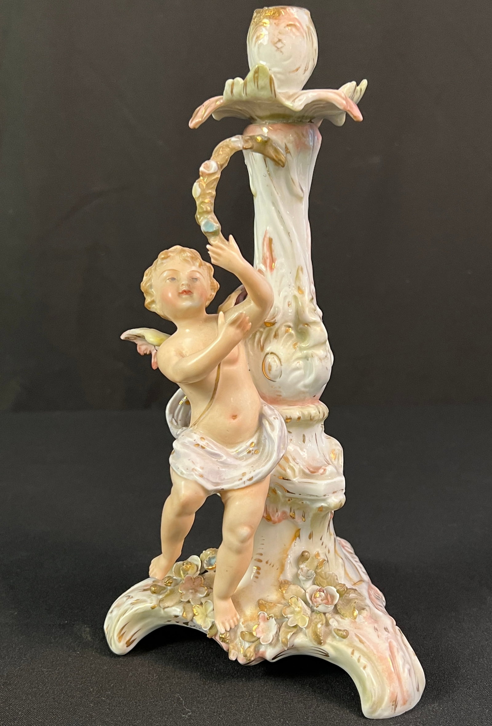 19th Century German Von Schierholz Porcelain Cherub Candlestick: A 19th century German porcelain Von Schierholz porcelain cherub candlestick in very good condition with minor old repair at candle cup. It measures 11" tall X 6" across X 6" deep.
