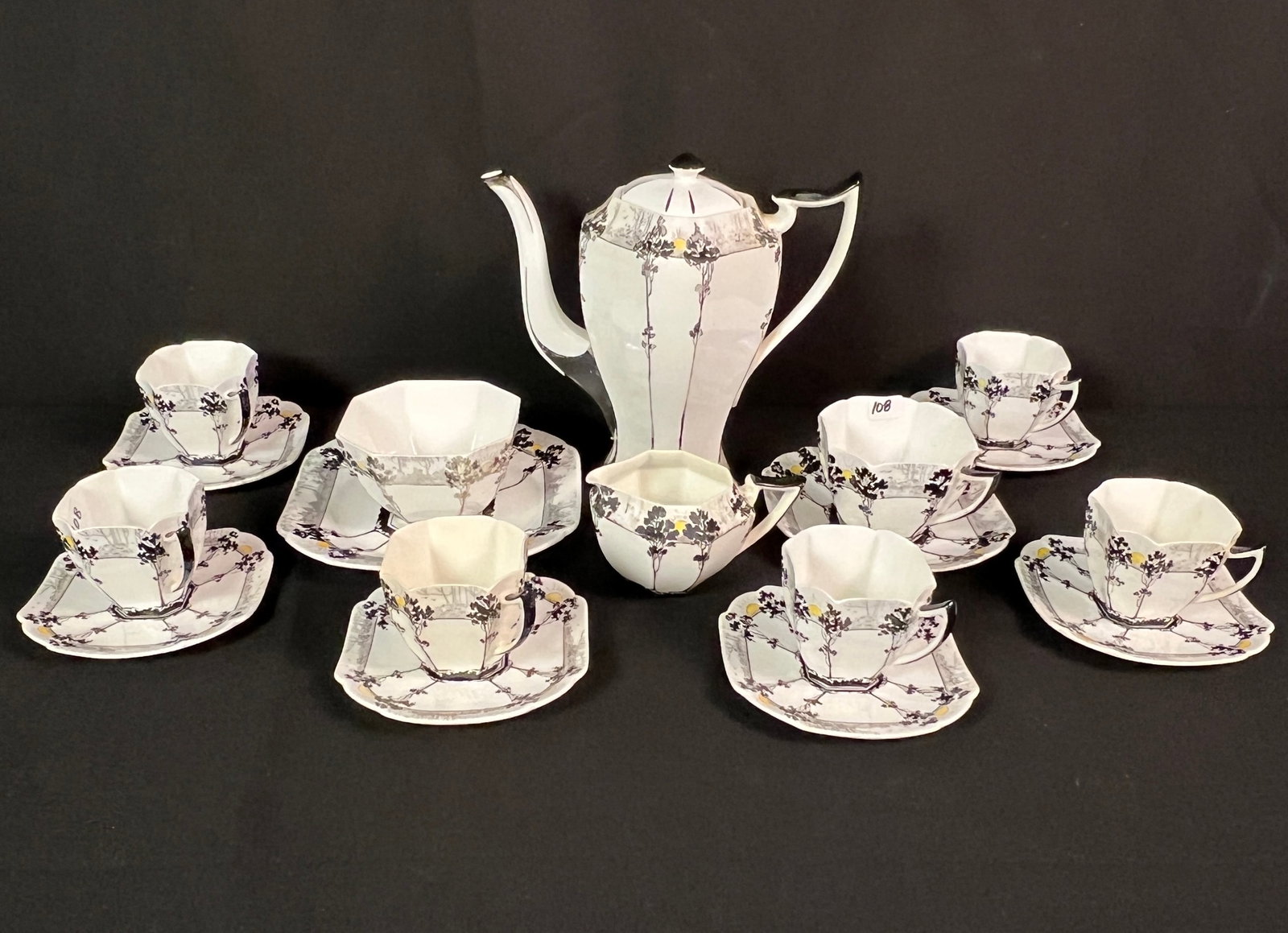 Shelley Bone China Tea Set "Trees and Sunset" c.1926: An Art Deco Shelley China Tea set in the "Trees and Sunset" pattern c. 1926 to include teapot, creamer, sugar bowl with underplate, 6 teacups and saucers, and one large coffee cup and saucer. All in