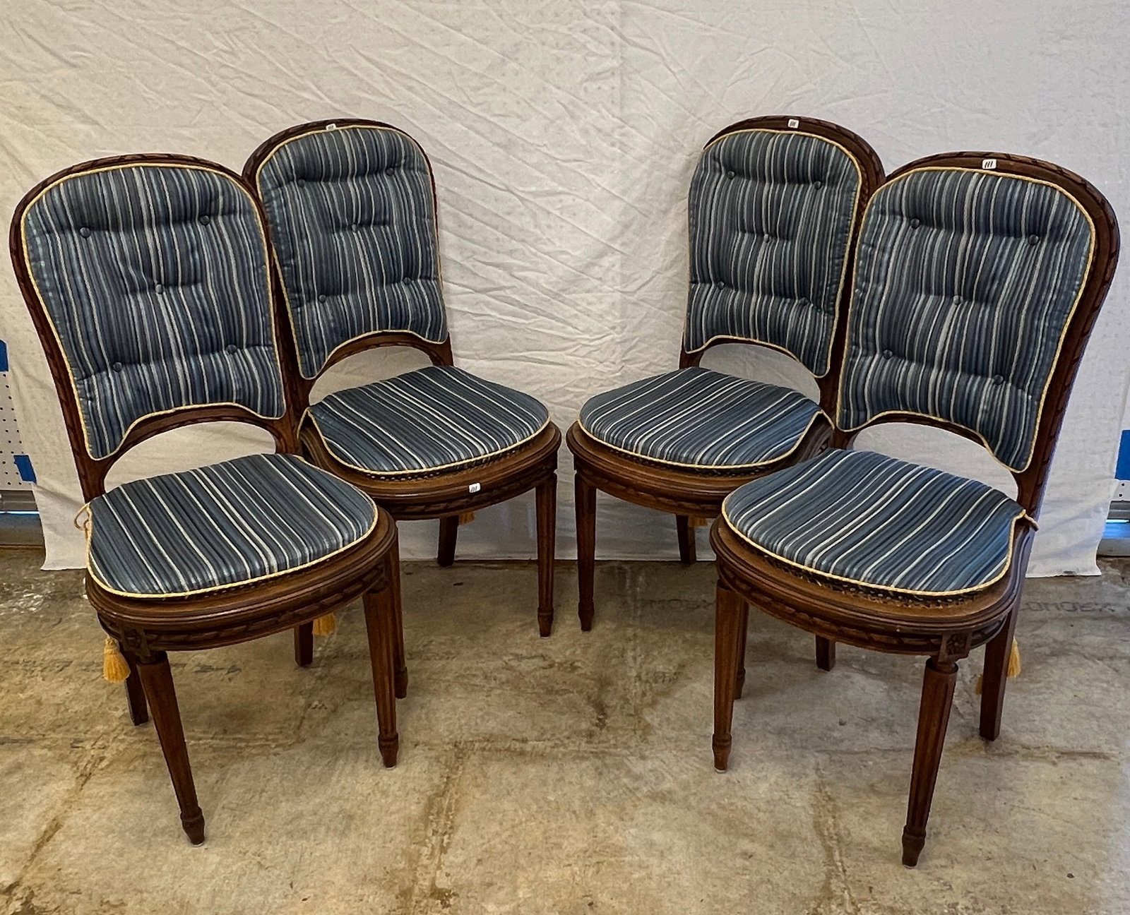 Set of Four Antique French Chairs: A set of four ribbon carved caned seats chairs in Circassian Mahogony. Chairs feature tapered legs and blue button-tufted pad upholstery. All four chairs are in excellent condition and each measure