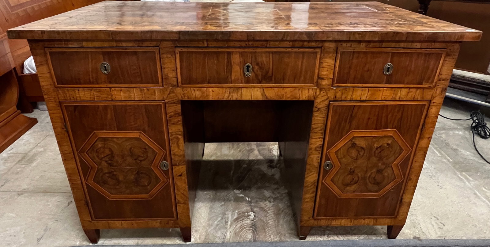 18th Century French Marquetry Inlaid Desk: An exquisitely inlaid Marquetry writing desk featuring oyster walnut veneer and elaborate craftsmanship throughout. This desk features three drawers and two doors on the side of the sitter, the