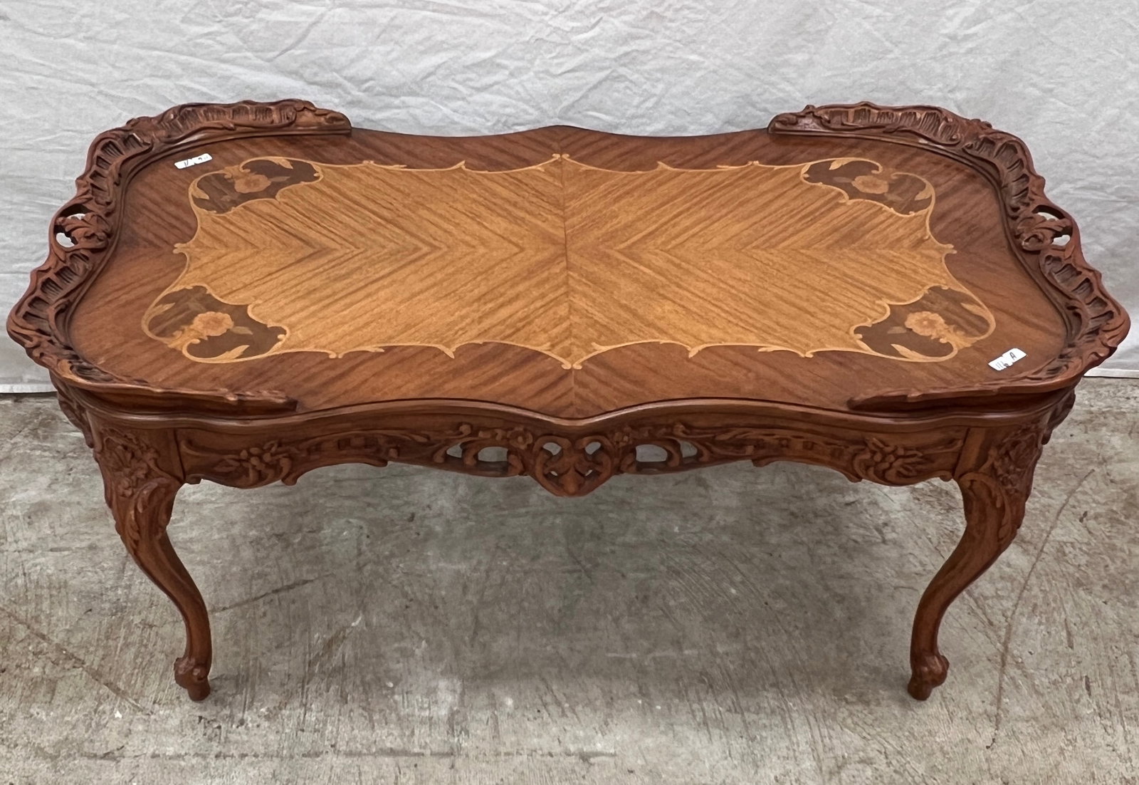 French Inlayed Coffee Table: A French floral and pierced carved coffee table with inlays and piecrust edging. In excellent condition with original finish, this table measures 18" tall X 39" across X 21" deep.
