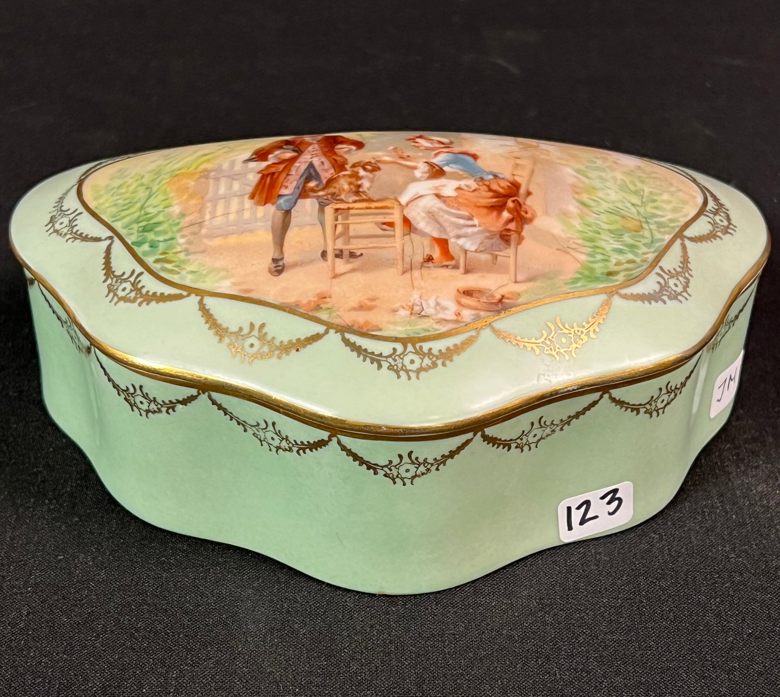 Limoges Porcelain Lidded Trinket Box c.1900's: An antique Limoges French porcelain lidded trinket box with a scene of an 1800's couple playing with a dog. In excellent condition, it measures 3.25" tall X 7.5" long X 4.5" deep.