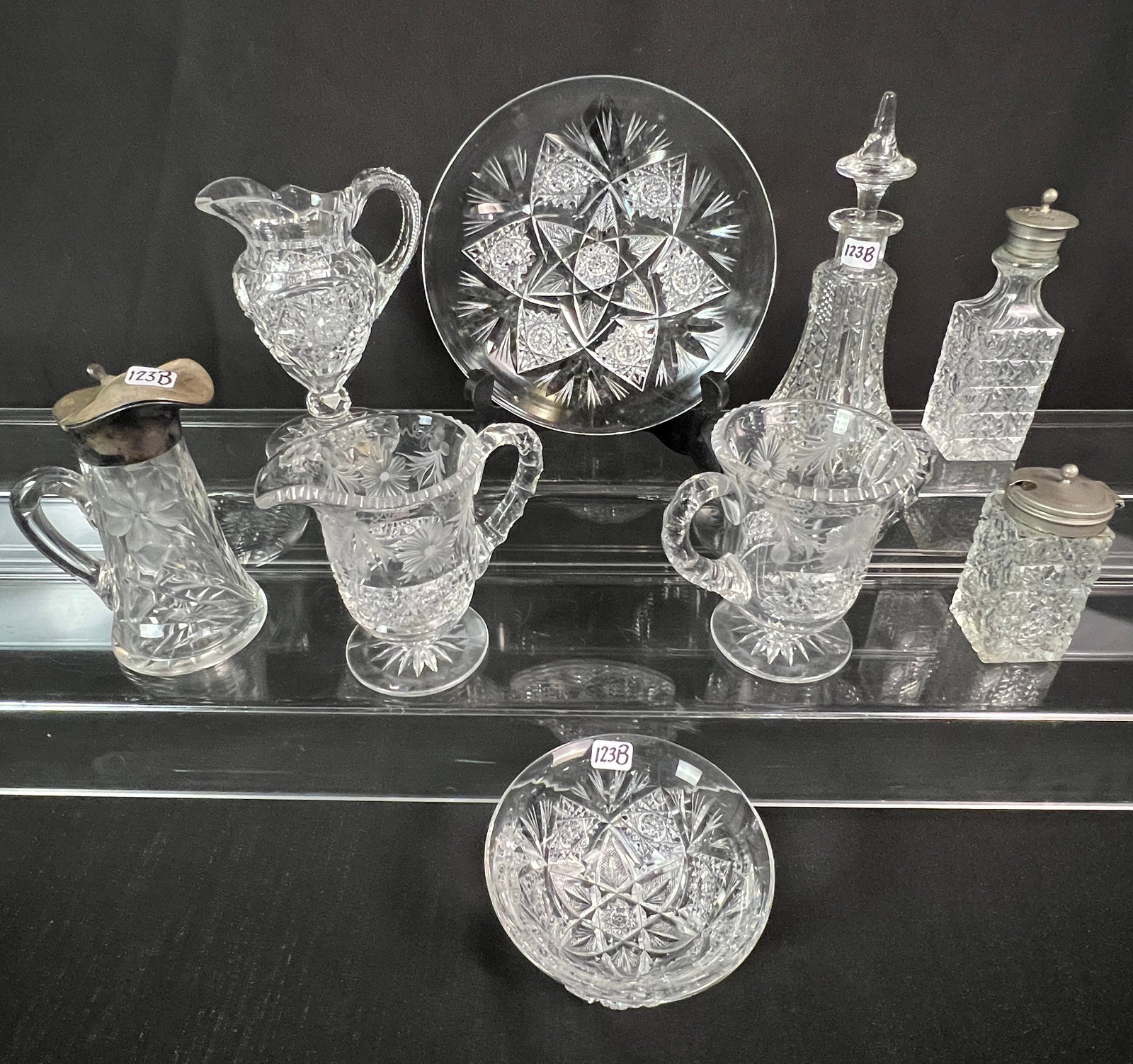 Victorian Brilliant Cut Crystal Group: A Victorian brilliant cut crystal group to include a floral syrup pitcher (6" tall), a floral handled creamer and sugar (5" tall each), a brilliant cut crystal creamer (6" tall), a cross hatched cut c