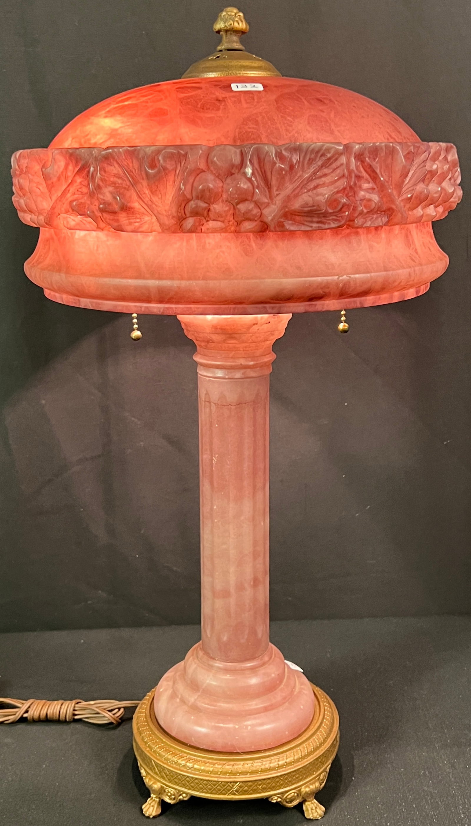 Pink Alabaster Table Lamp c. 1900: A pink alabaster table lamp from the turn of the century. Lamp features a cast metal base, fluted column stem, and grapevine carved shade. This lamp measures 23" X 13"