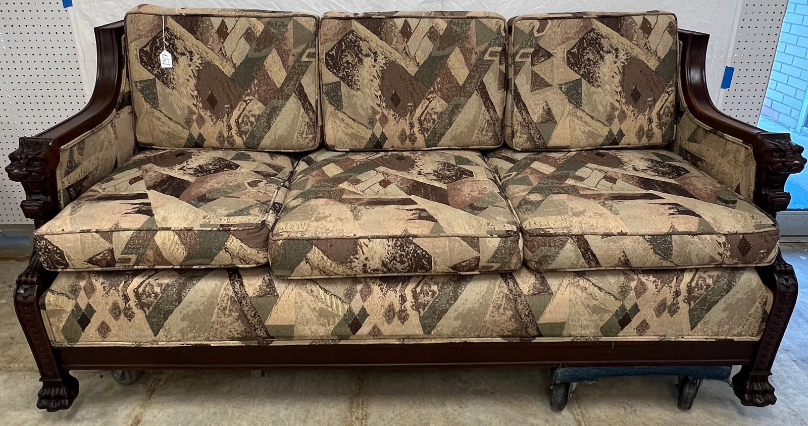 Oversized Victorian Sofa with Carved Lion Heads: A Victorian mahogany profusely carved sofa with contemporary upholstery that features screaming lion arm fronts, paw feet, mahogany frame. In excellent condition, it measures 37" tall X 77" across X 3