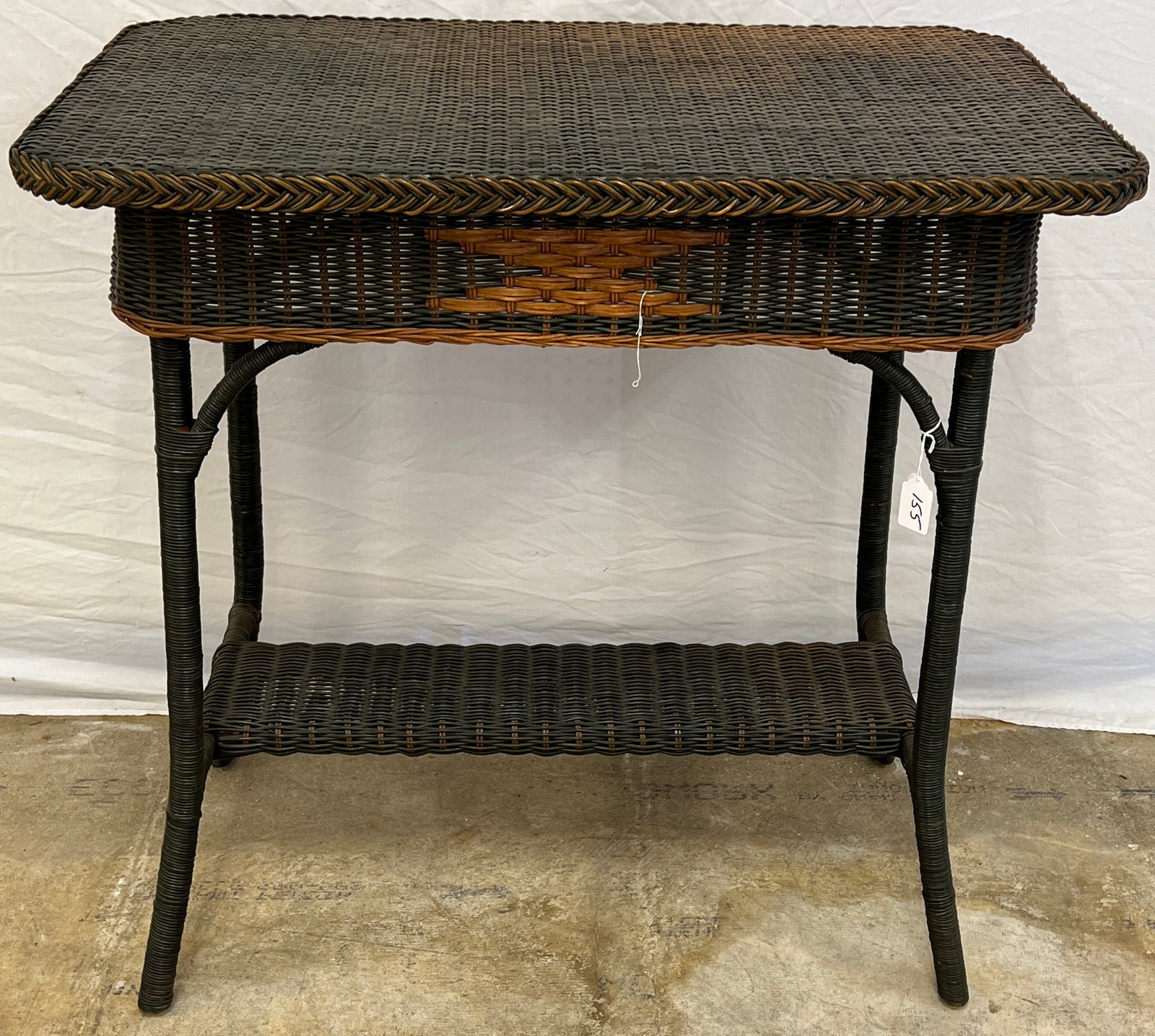 Palecek Wicker Plant Table: A contemporary Palecek wicker plant that has green and brown wicker and an undershelf in very good condition. Top Shows fading.