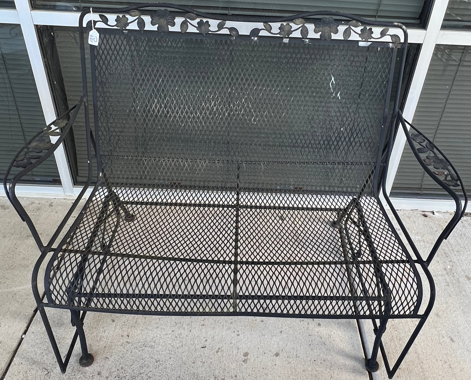 Iron Armed Glider Bench: Iron and floral decorated garden glider bench. In good, as found condition, it measures 36" tall X 47" across X 16" deep.