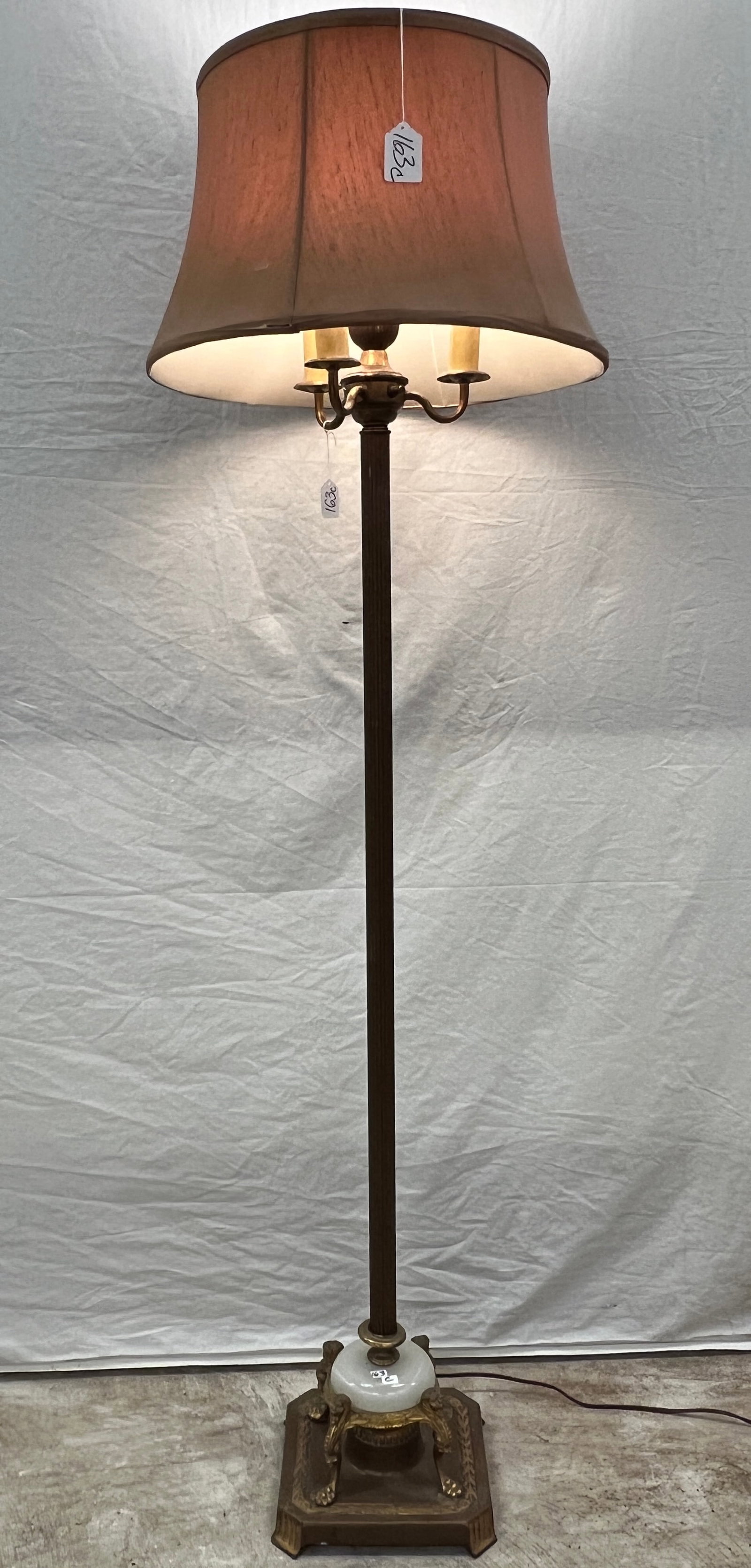 Fancy Brass Floor Lamp: A 1930s brass floor lamp with lionhead base, glass insert, in good, working condition. It measures 63" tall.