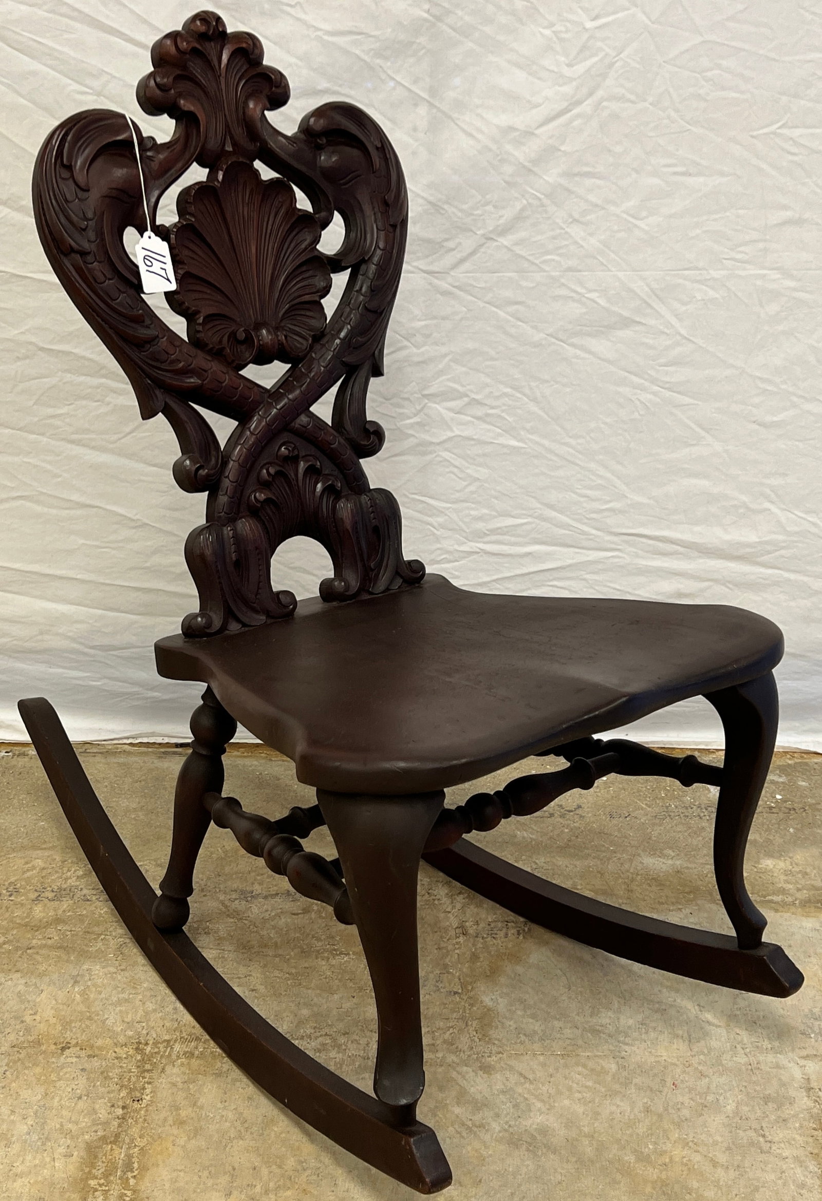 Elaborately Carved Black Forest Rocker: An elaborately carved black forest style rocker depicting dolphins and shell. This piece features beautiful craftsmanship and measures 35" tall X 19" across X 18" deep.
