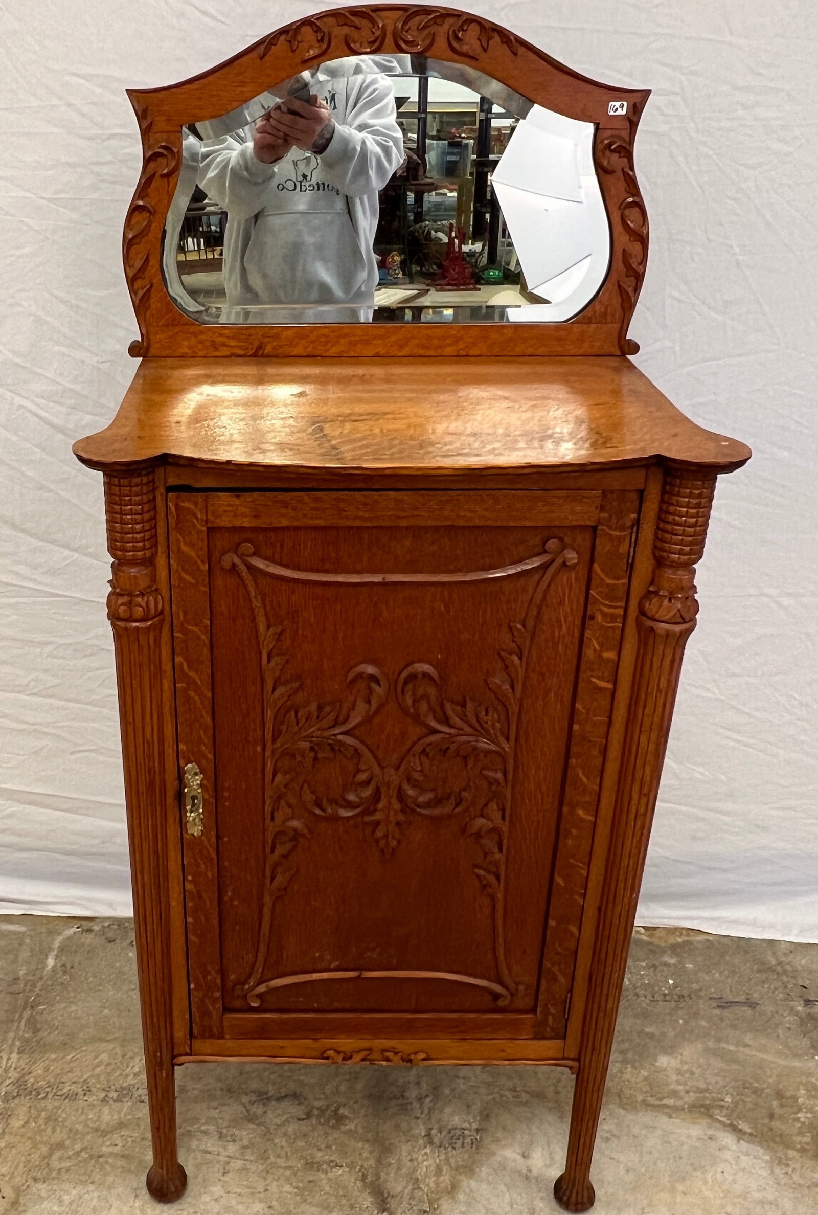 Victorian Oak Carved Mirrored Back Music Stand, c.1890s: A Victorian quarter sawn oak locking music cabinet that features a fancy framed back mirror with beveled glass and carved frame, single door bottom with leaf carvings, pillared legs with acanthus