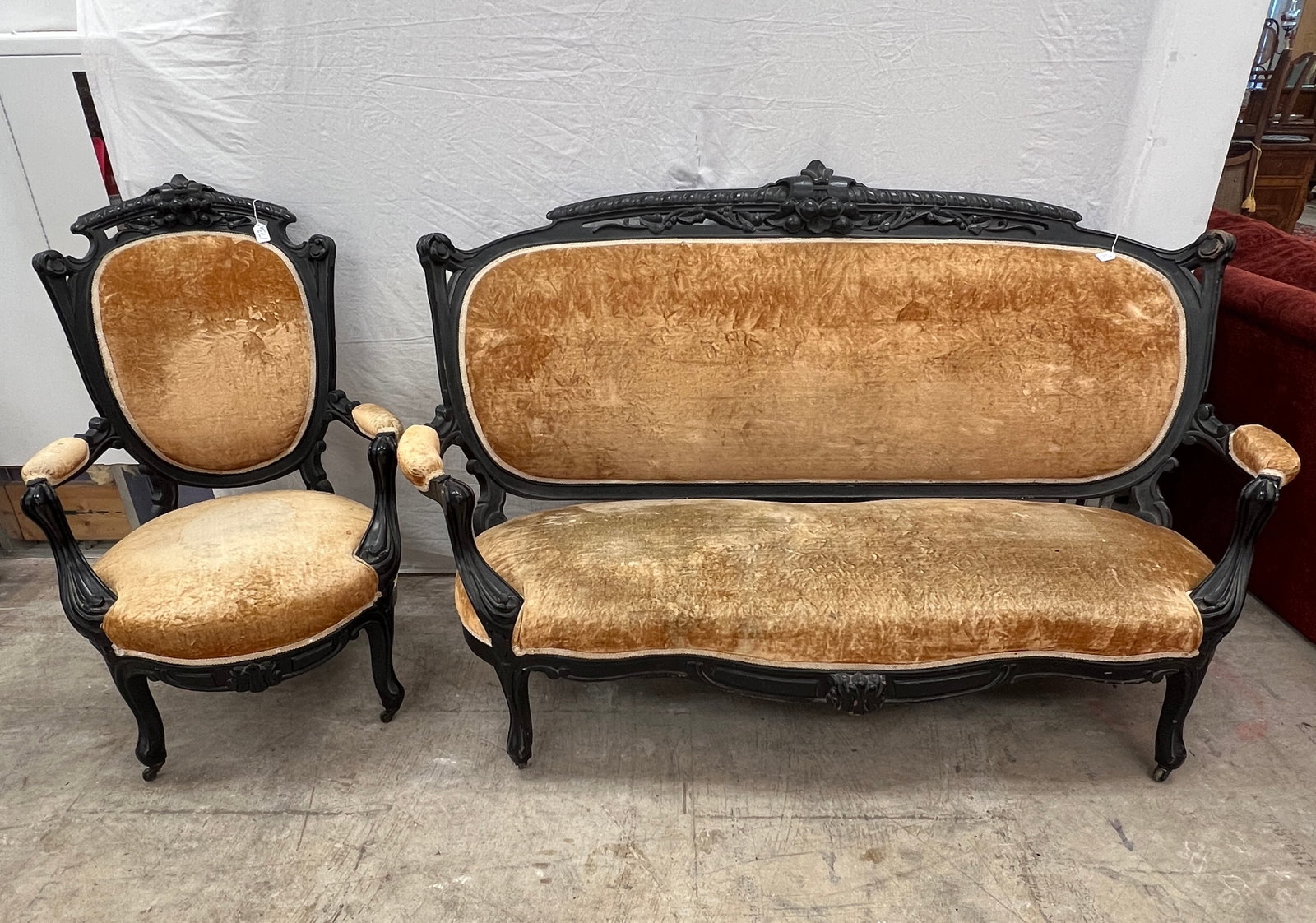 Two Piece Victorian Carved Parlor Suite: A two piece pierced carved Victorian parlor suite to include an oversized sofa and chair in an ebonized finish. In as found condition. The sofa measures 43" tall X 73" across X 22" deep and the chair 