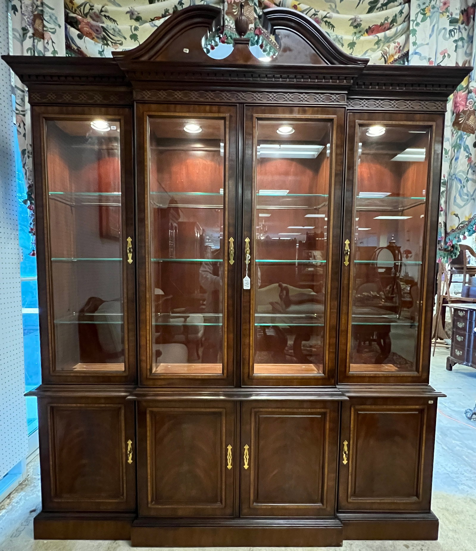 Drexel Chinese Chippendale Breakfront: A Chinese Chippendale Mahogany breakfront by Drexel with banded inlays, arched pediment, beveled glass door fronts, and glass adjustable shelving that lights up. This 2-part China breakfront is in