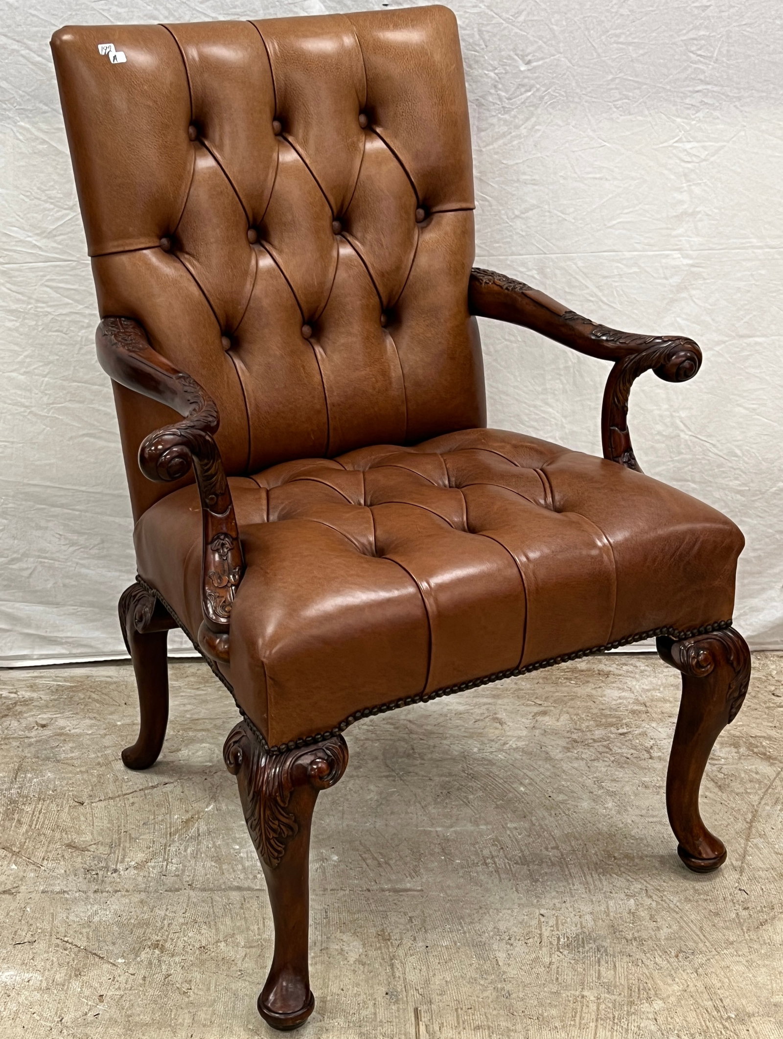 George II Style Eage Carved Leather Armchair: A high quality button tufted George lll style cocoa brown leather armchair with floral carved arms and legs in excellent condition.