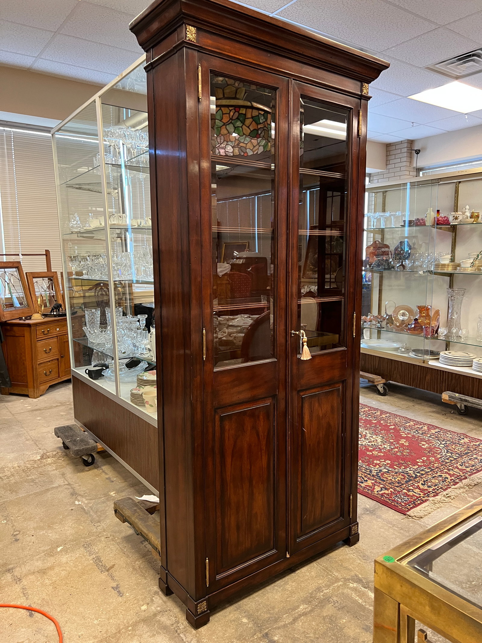 French Polished Double Door China Display Cabinet: A Federal Style French polished mahogany double door cabinet glass front illuminated cabinet by Theodore Alexander that features guided brass details, original key in excellent condition.