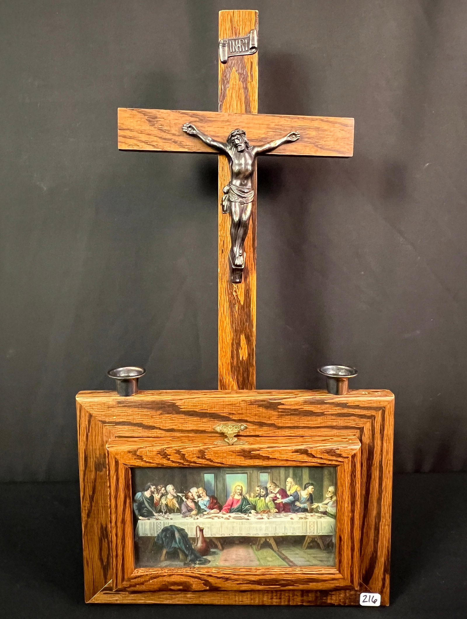 Wall Mounted Exhumation Box: A 1900's Exhumation box that includes wooden cross and drop down door that contains, Eucharist plate, holy water bottle, candles and spoon. Used to give last rites to shut ins. Has a scene of the last