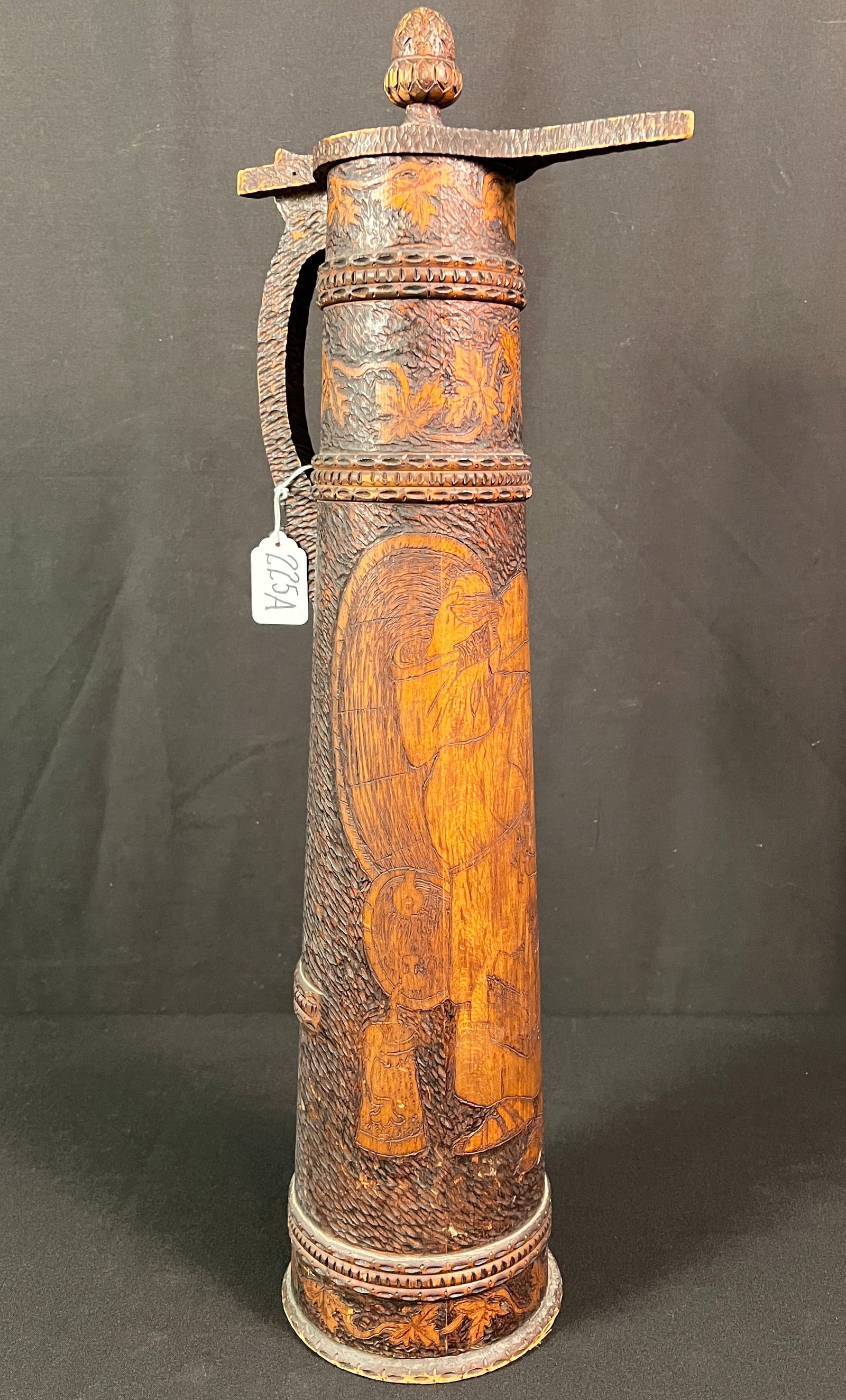 Folk Art Pyrograph Tankard: A large Folk Art pyrographic covered tankard depicting a monk drinking with grapevine foliage. In good condition it measures 23" tall X 8" across.