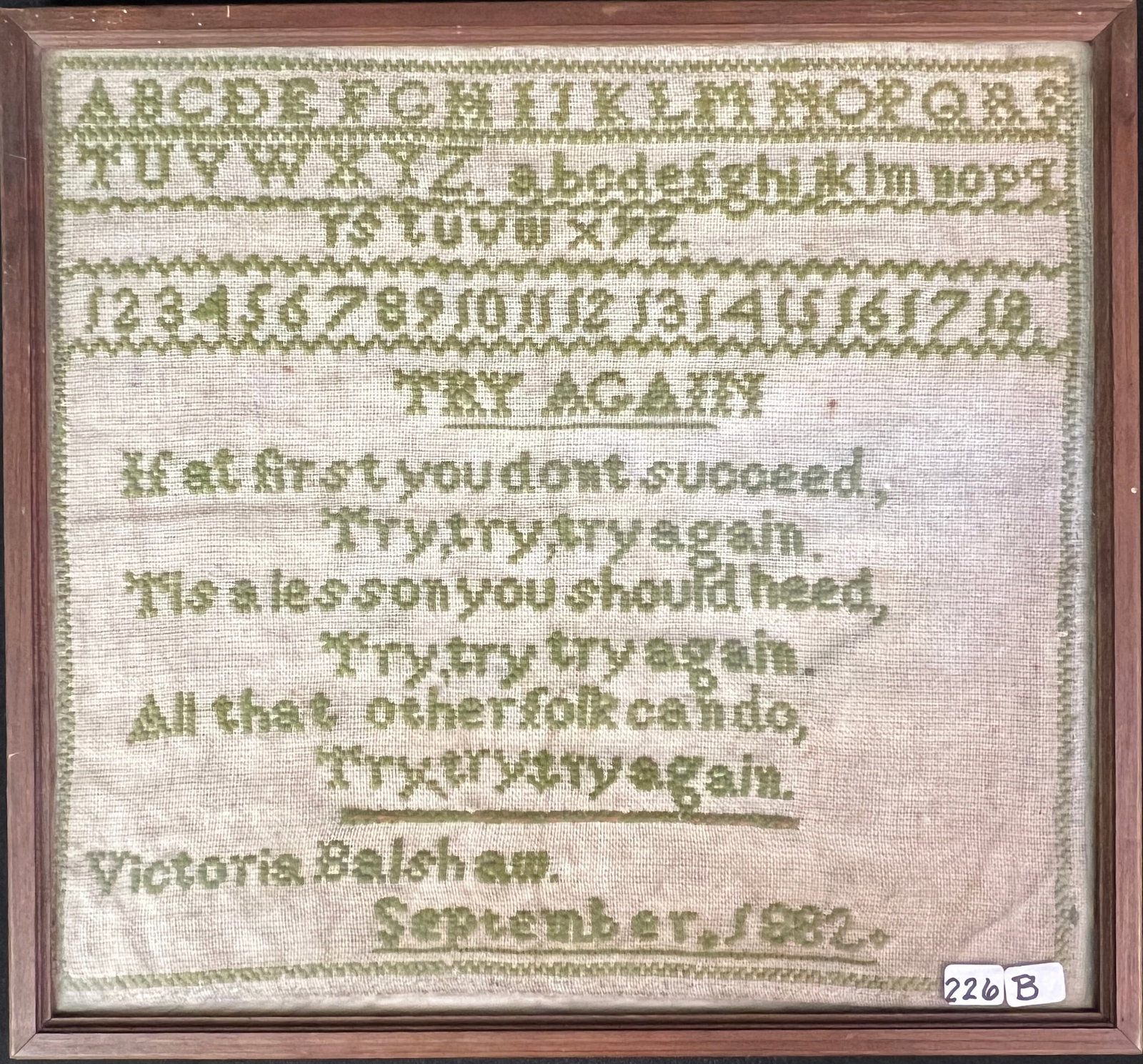 Try, Try, Try Again' Sampler by Victoria Balshaw, ca.1882: A sampler ca.1882 by Victoria Balshaw that depicts the alphabet, numbers, and a poem titled "Try Again". In green thread on canvas, this piece measures 13" tall X 14" across framed.
