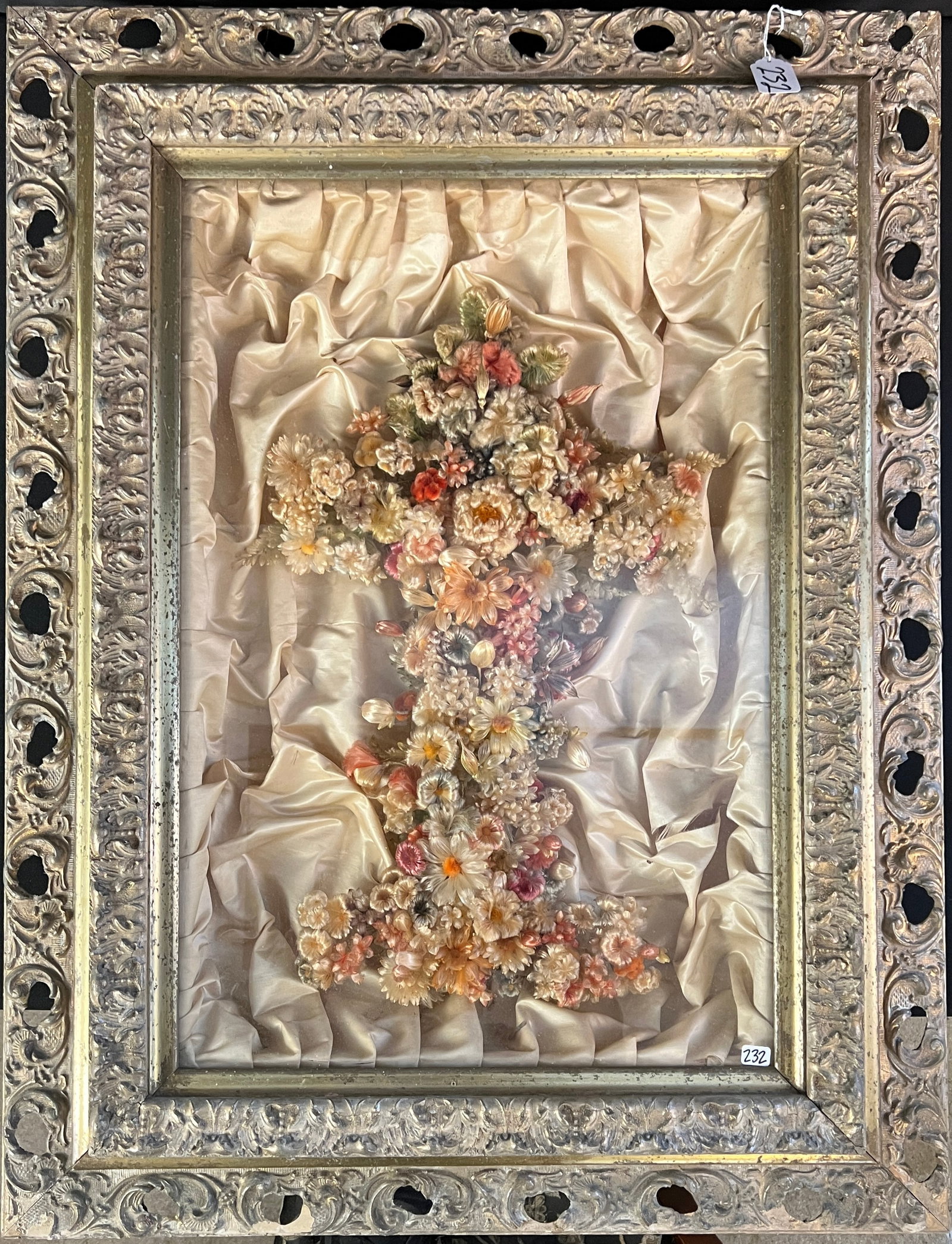 Victorian Wonderment of Silk Floral Cross: A hand made silk wonderment in a period gilded gesso shadowbox frame on a white tufted satin background depicting a floral crucifix c.1880's in excellent condition.