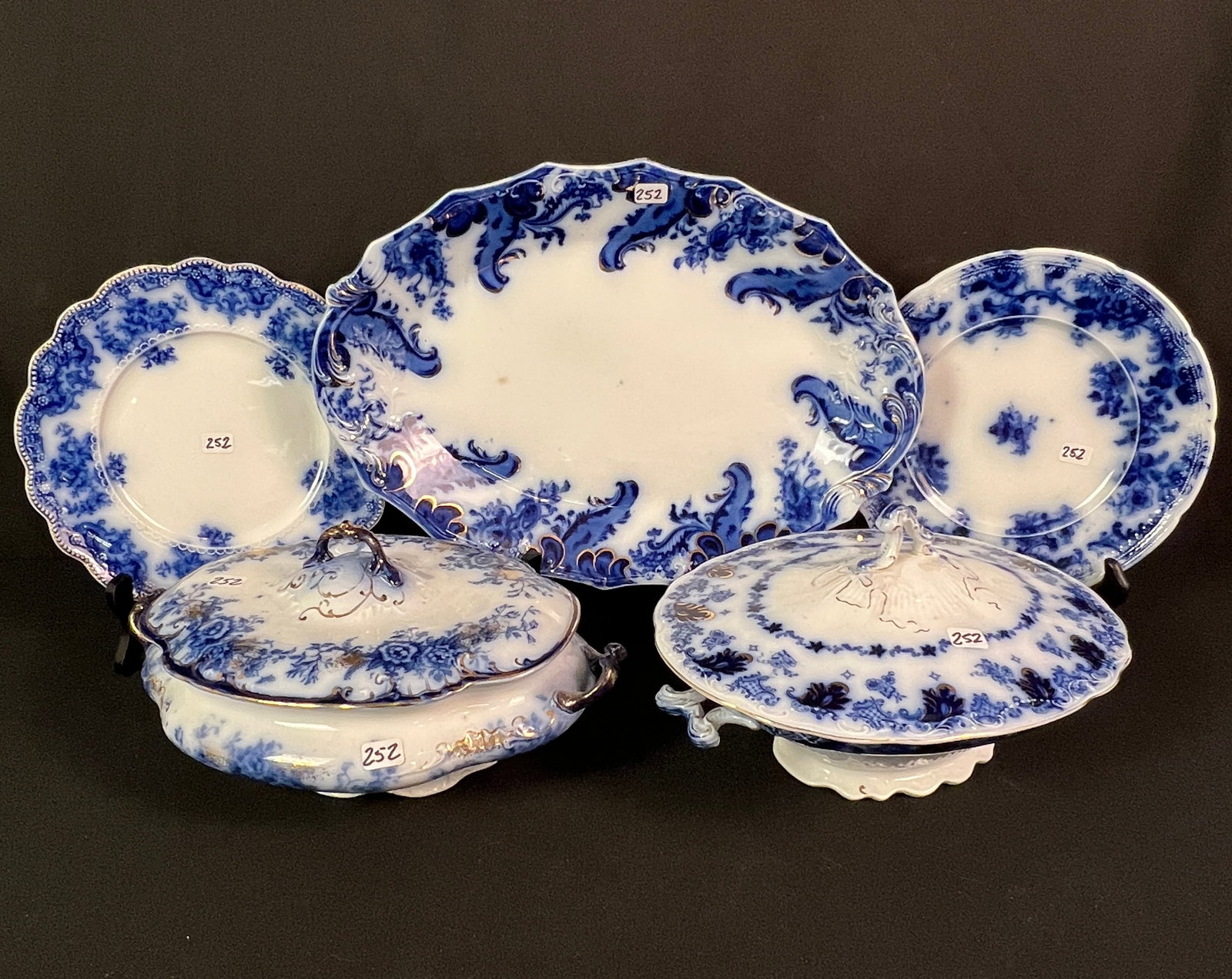 Flow Blue Platter, Plates and Covered Tureens: A group of flow blue to include a large decorative platter in 'Argyle' patter with gold accents (15" long X 10" across), a handled and covered tureen floral with gold accents (4.5" tall X 11" across