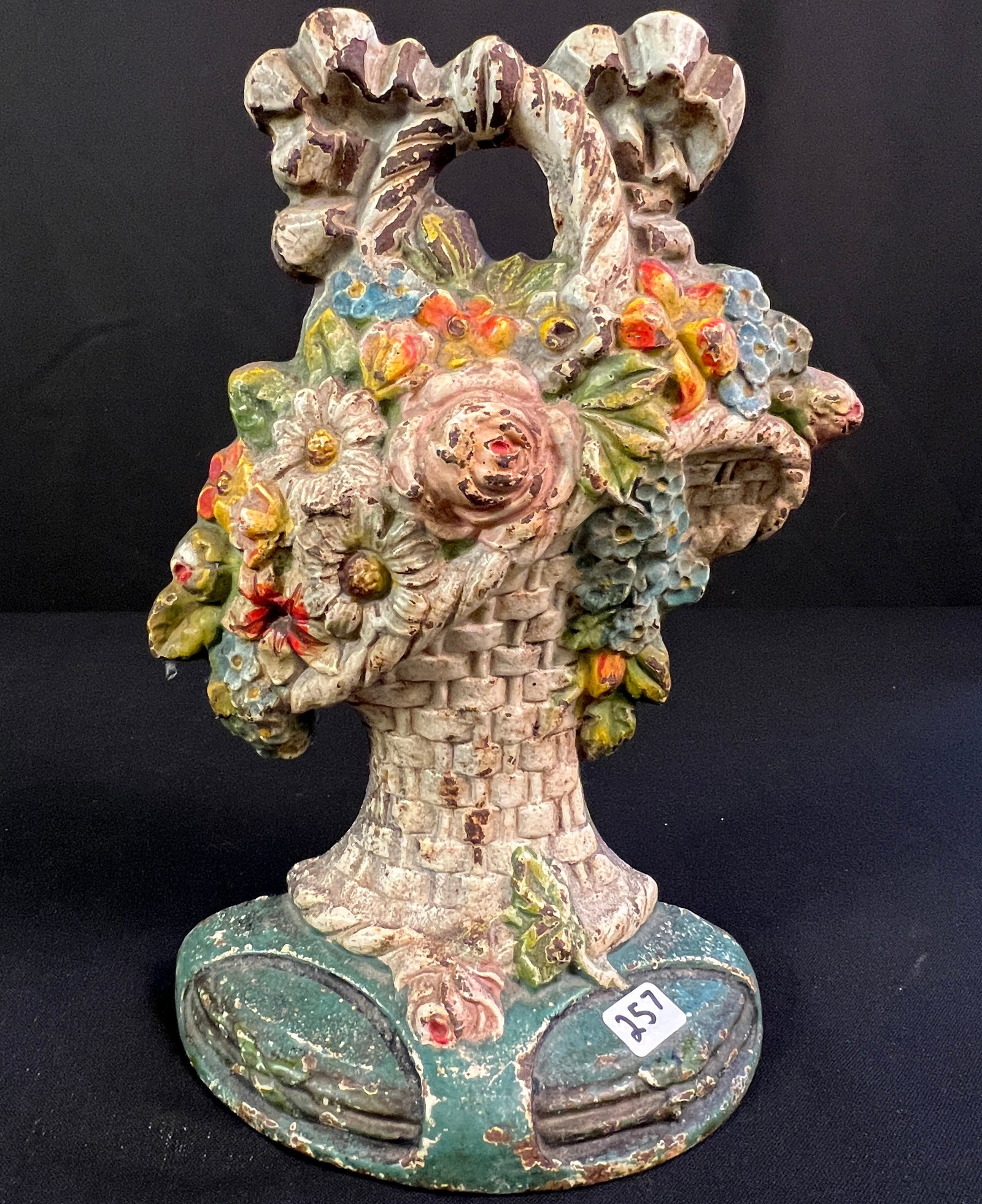 Floral Basket Doorstop: A 1920's floral basket painted cast iron door stop. Some age wear to paint otherwise in good condition, measures 10" tall.