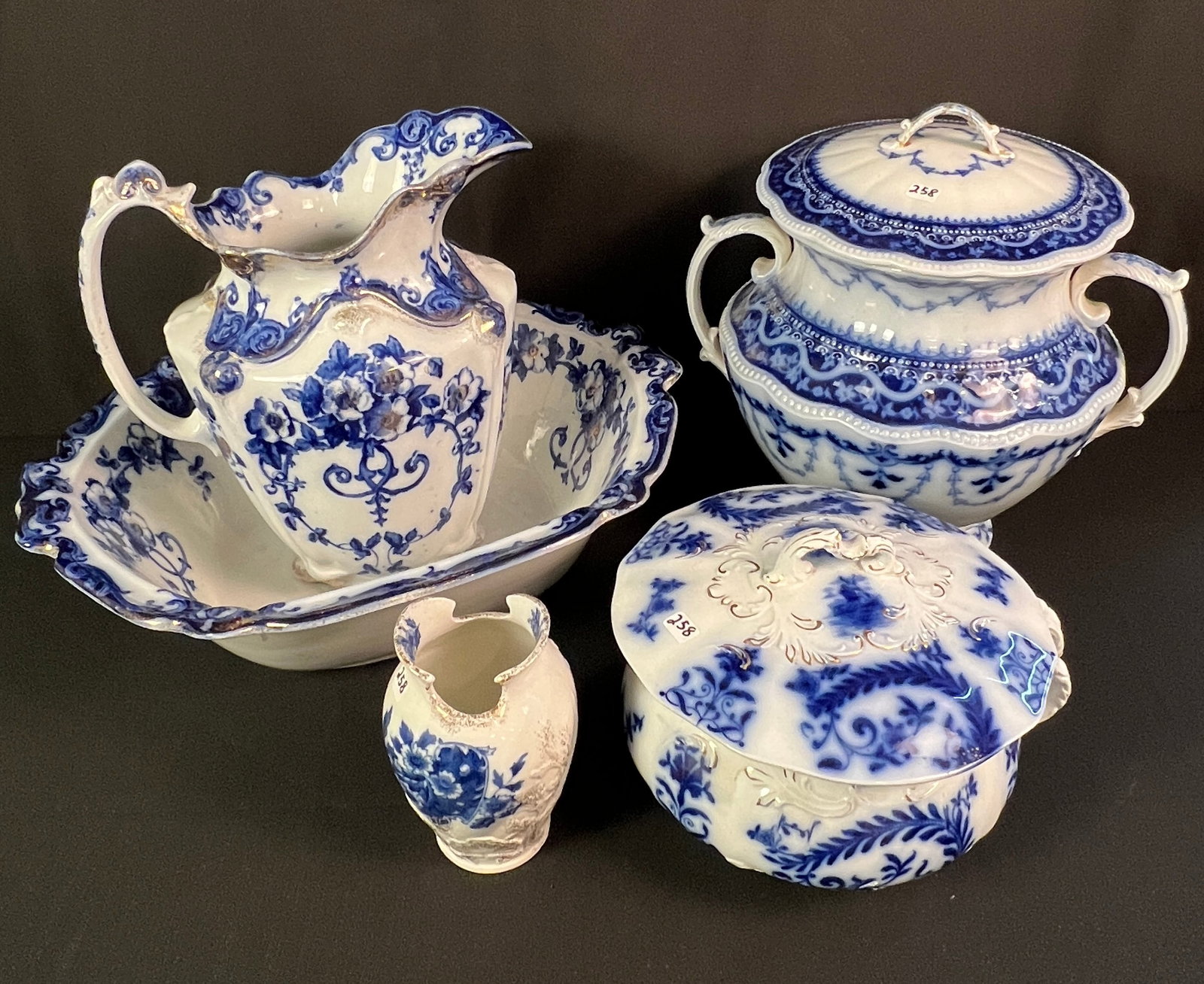 Flow Bule Water Pitcher with Bowl, Chamber Pots and Toothbrush Holder: A group of flow blue to include a fantastic oversized water pitcher with bowl in the "Queen" pattern by W. Adams and Co. (pitcher measures 12.5" tall, bowl measures 18" long X 15.5" across), a