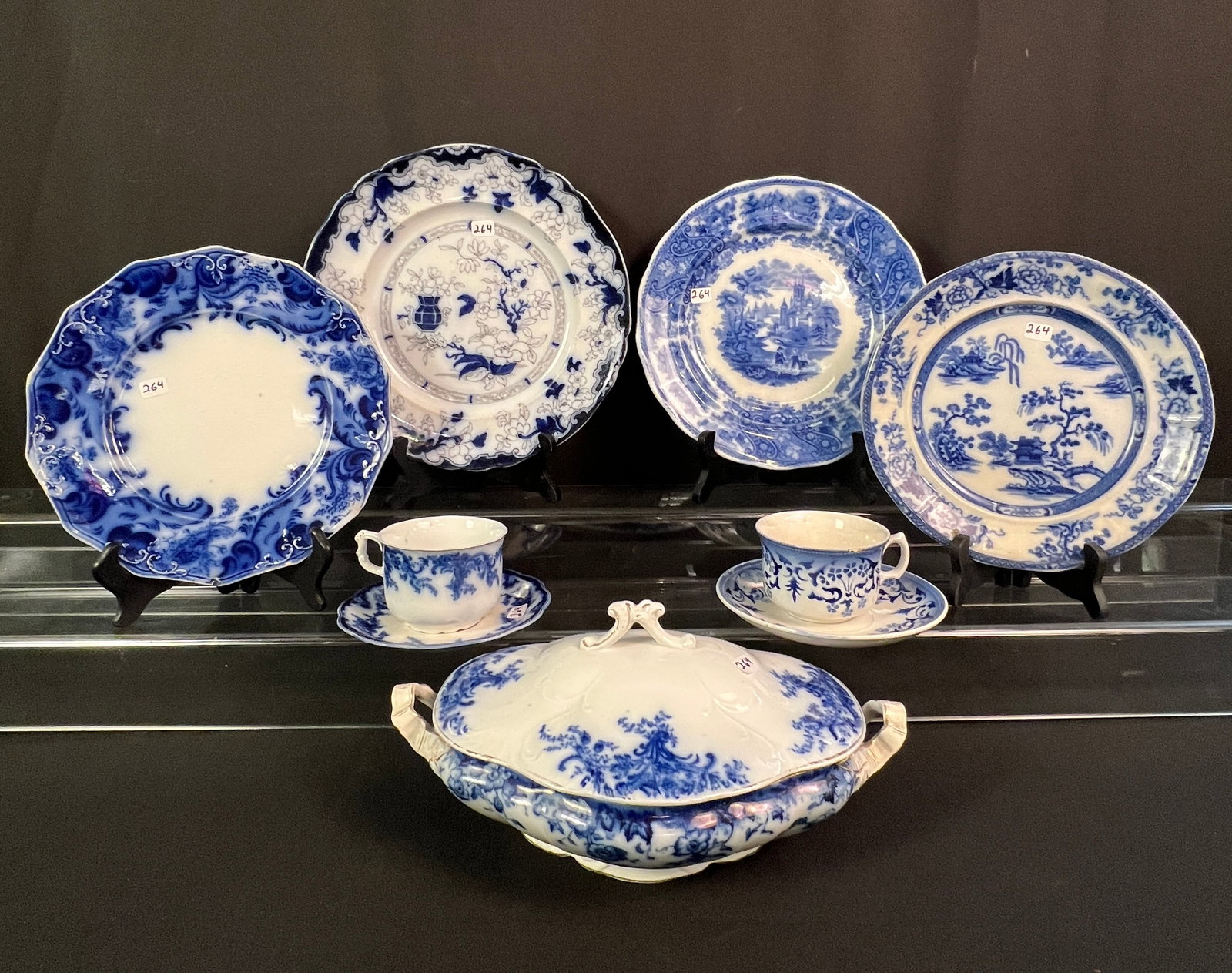 Flow Blue Tureen, Plates and Teacups: A group of flow blue to include a covered soup tureen in the "Vermont" pattern by Burgess & Leigh (measures 6" tall X 12" across), 4 assorted large plates and 2 assorted teacups with matching saucers.