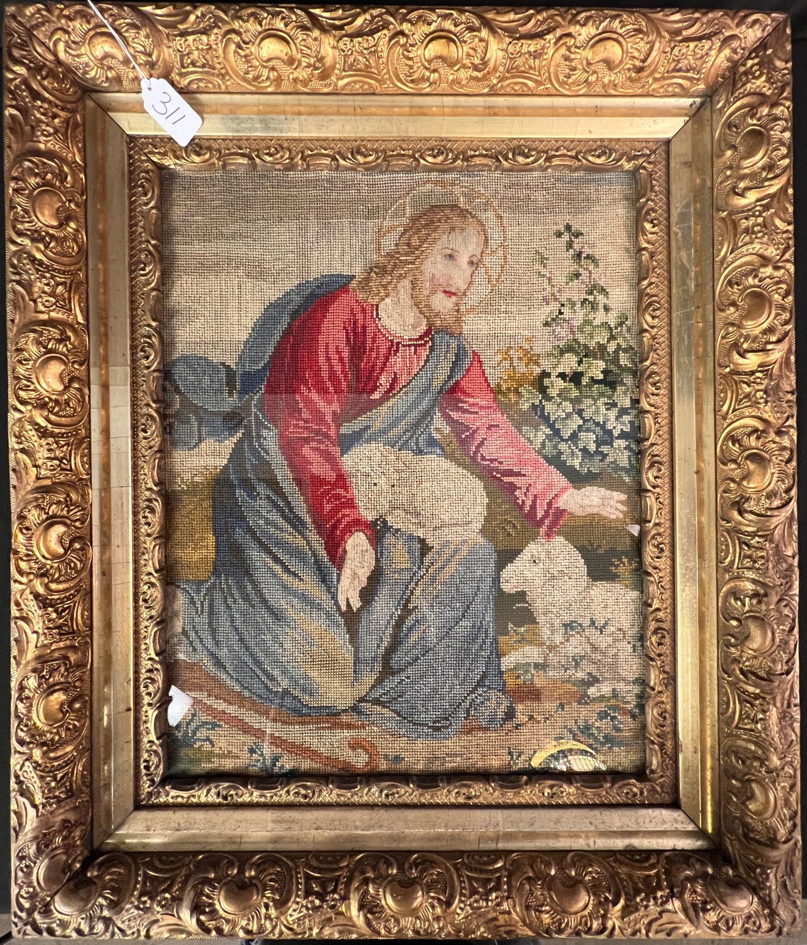 Needlepoint Tapestry of Jesus Christ: A framed religious needlepoint tapestry depicting Jesus Christ with two lambs. This intricate handmade needlepoint is in a decorative gold-colored frame. In great condition, with some light wear to