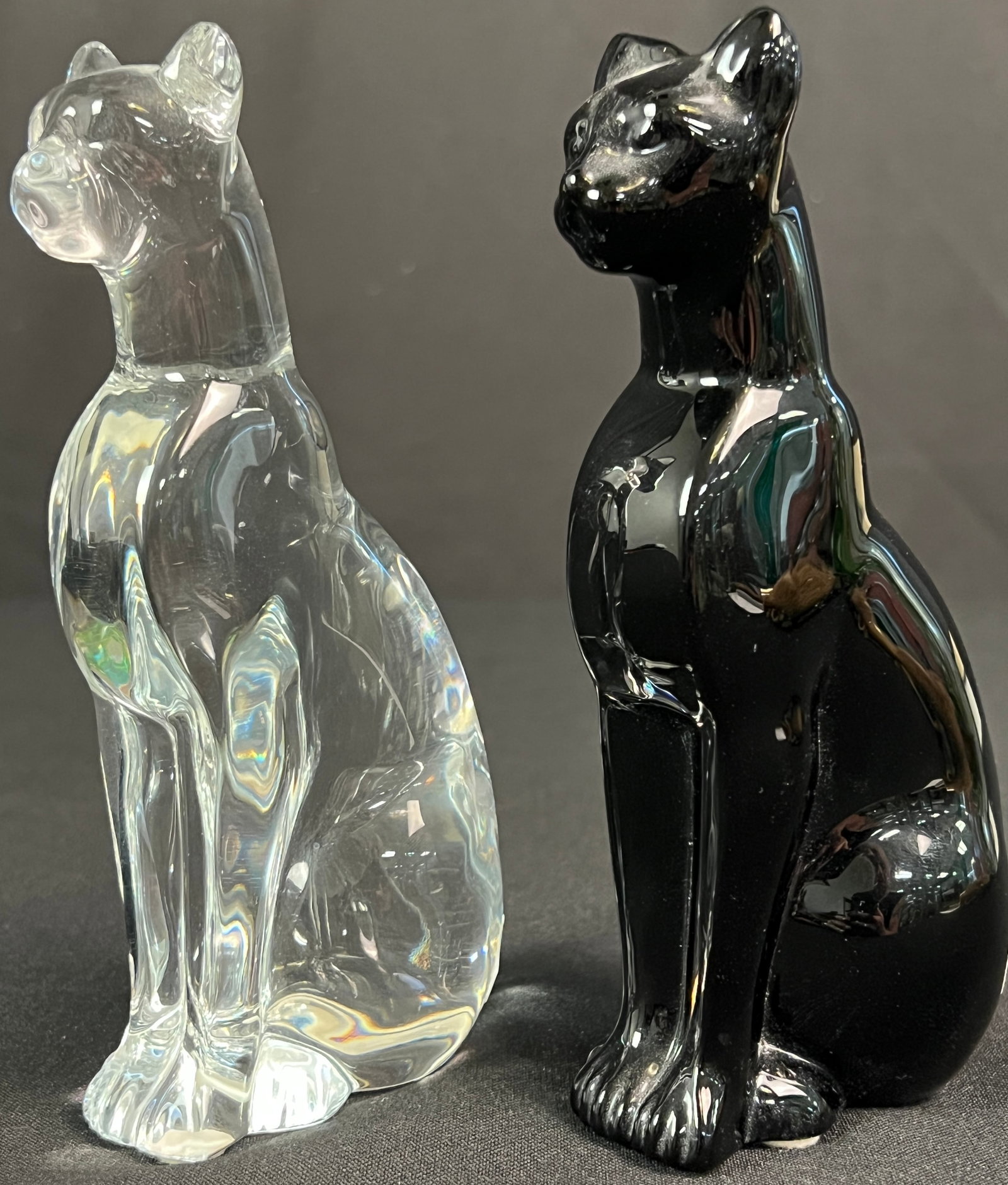 Pair of Baccarat Crystal Cats: A pair of Baccarat cat figurines, one is clear and the other is black. These signed pieces are in excellent condition and each measure 6.25" tall X 3" deep.
