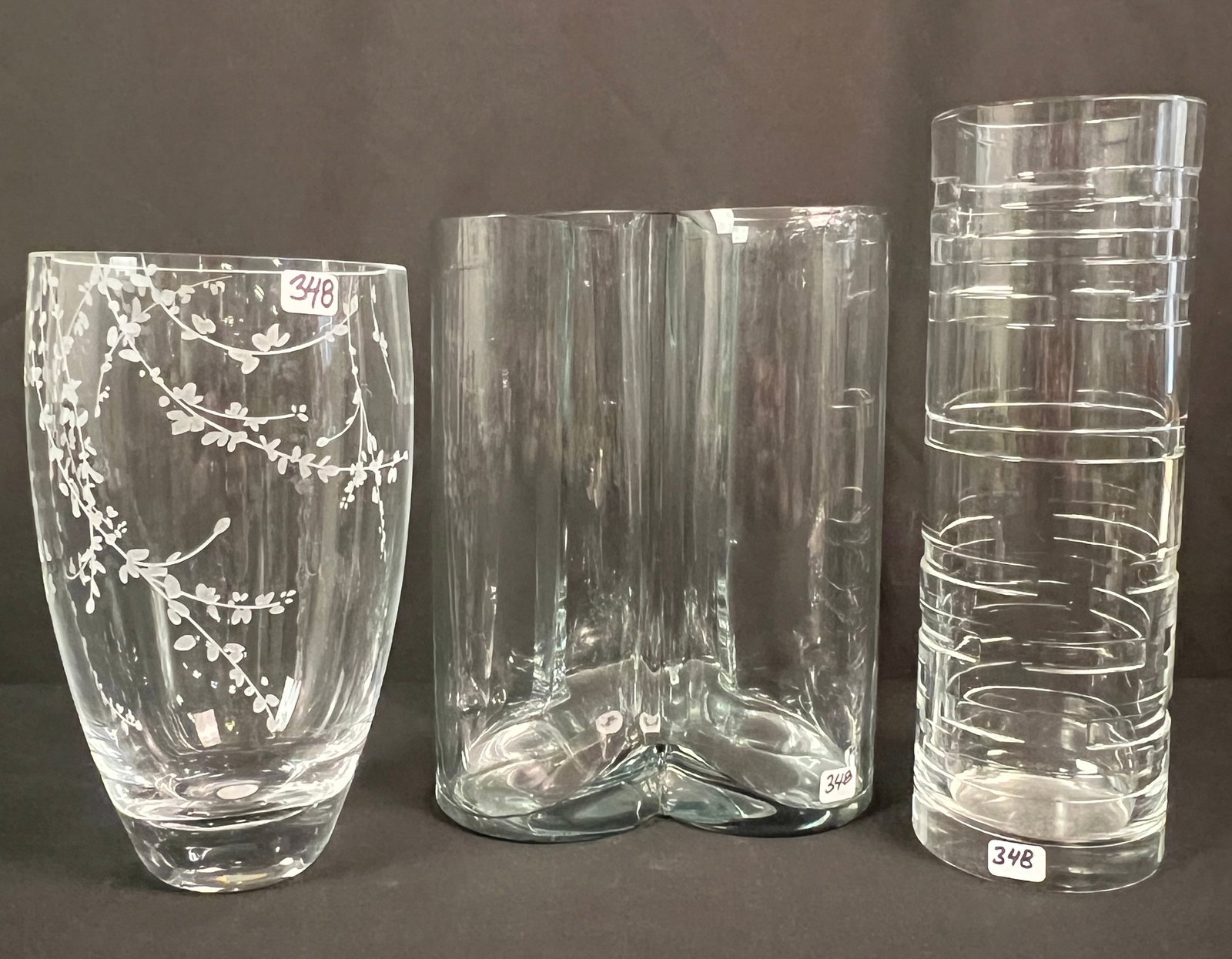 3 Designer Crystal Vases: 3 Designer Crystal vases to include a Kate Spade etched glass crystal vase (9" tall X 5" across), a Modernist Stiffel vase (11" tall X 3.5" across), and a clover shaped vase with a ground edge (9" tal