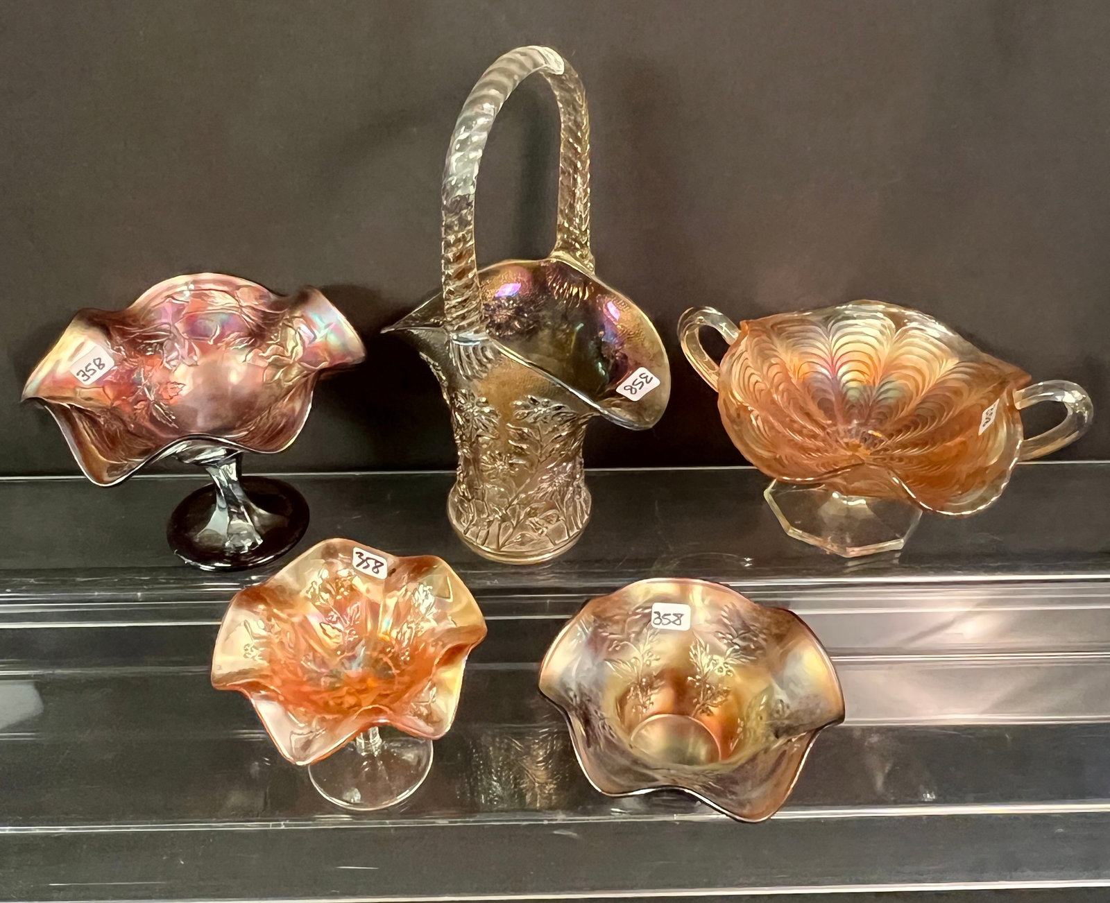 Group of Carnival Glass: A group of carnival glass to include a rose decorated compote, a leaf and berry decorated compote, a peacock tail double handled compote, a shallow bowl with berry and leaf design, and a basket of
