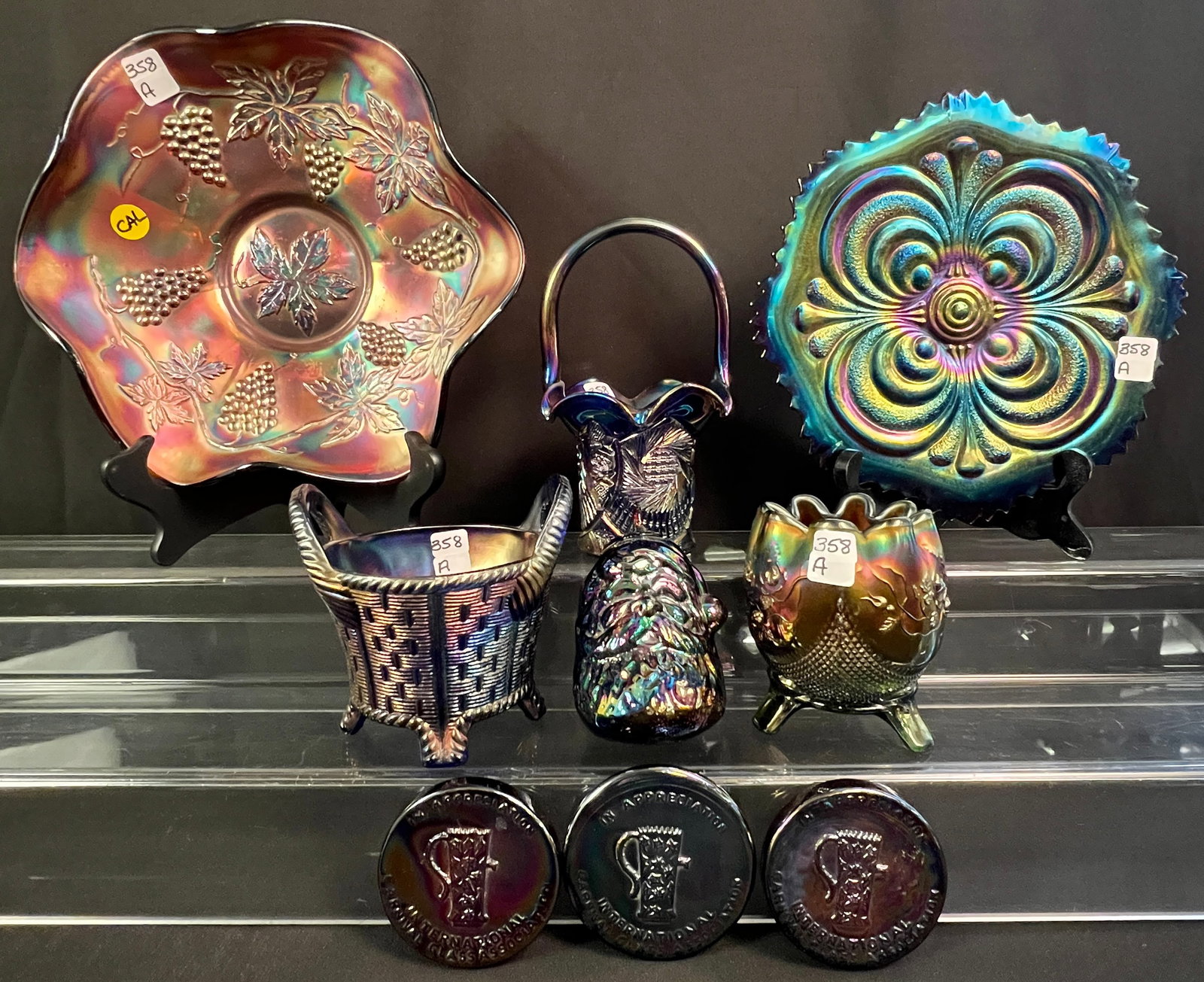 Group of Amethyst Carnival Glass: A group of amethyst carnival glass to include new and old pieces. Antique pieces to include footed rose bowl with ruffled edge, grapevine bowl (2" tall X 10" round), scroll embossed plate (1" tall X 9