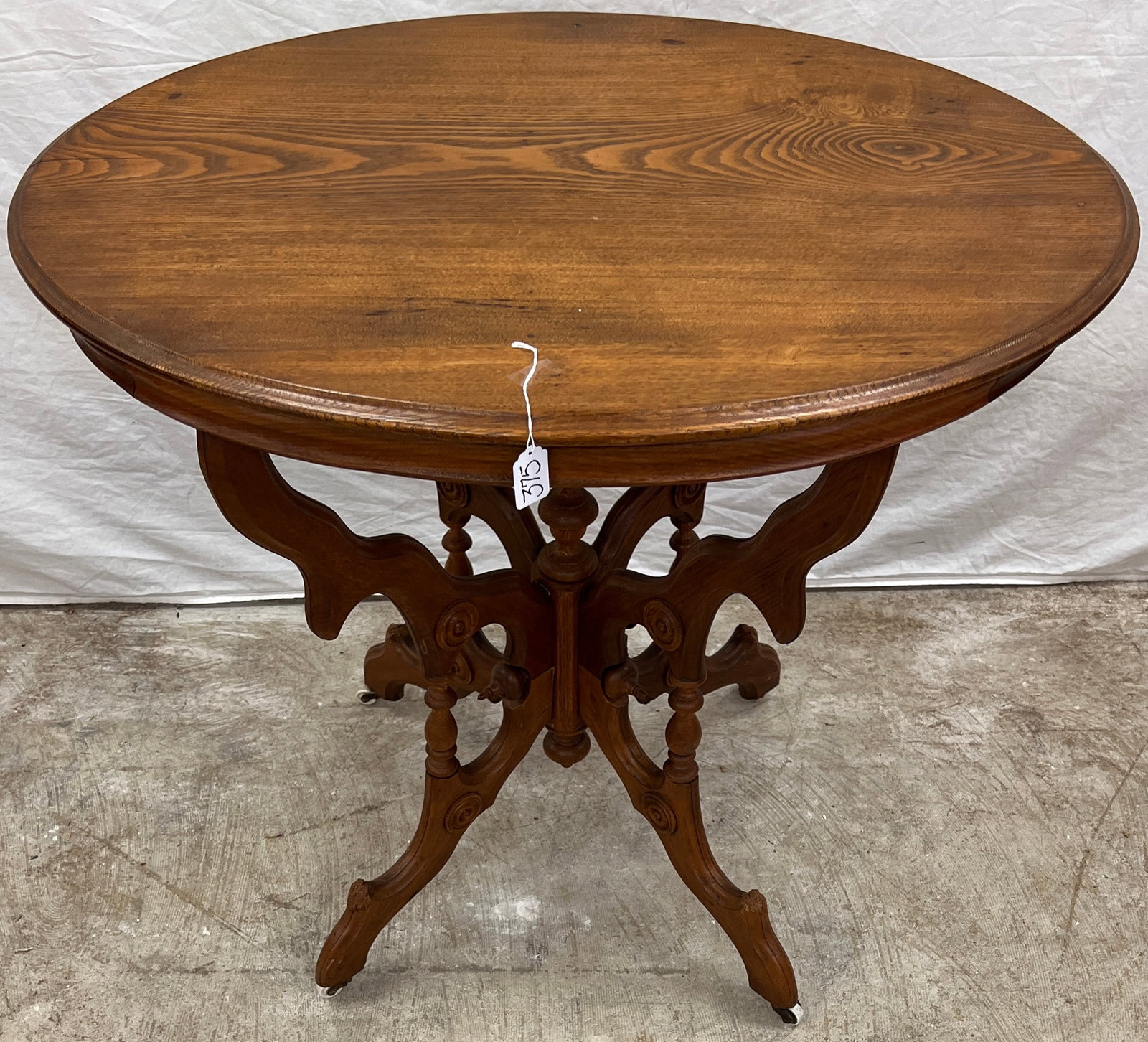 Victorian Oval Parlor Table: A Victorian ash parlor table with spindled base in refinished condition. Retains its original brass and porcelain castors. In good condition with puppy bites along all 4 legs, it measures 31" tall X