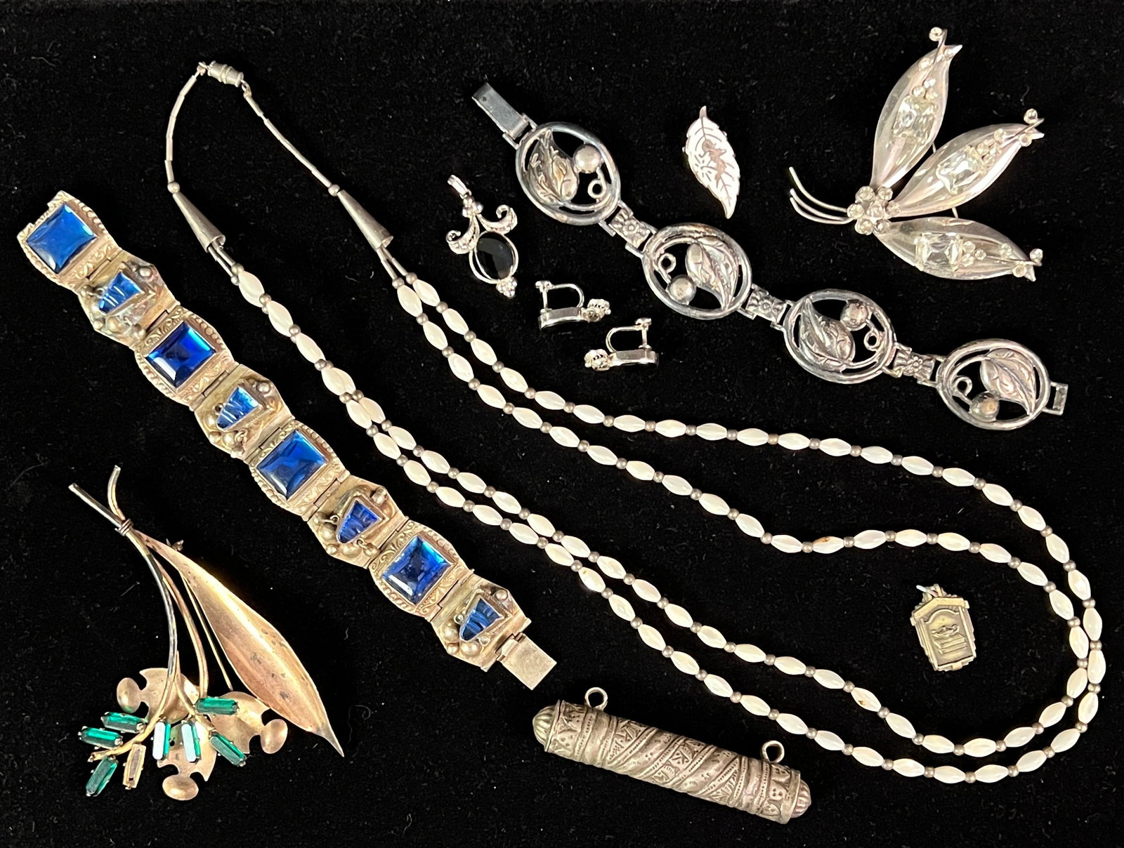 Group of Assorted Sterling and Silver Jewelry: A group of assorted jewelry to include a sterling vintage leaf bracelet, a sterling and white rhinestone pin, a sterling and green stone pin (missing one stone), sterling charm, one sterling inlay ear
