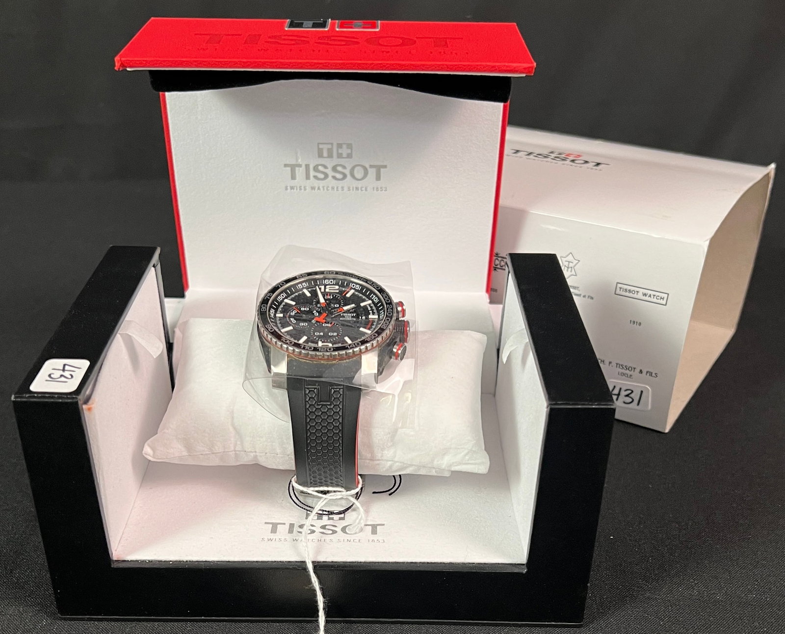 Tissot Men's Watch with Box: A Tissot PRS 516 Extreme Automatic Chronograph watch featuring a black dial with red accents and a black and red accented rubber strap. It features a stainless steel case with a black PVD coating,