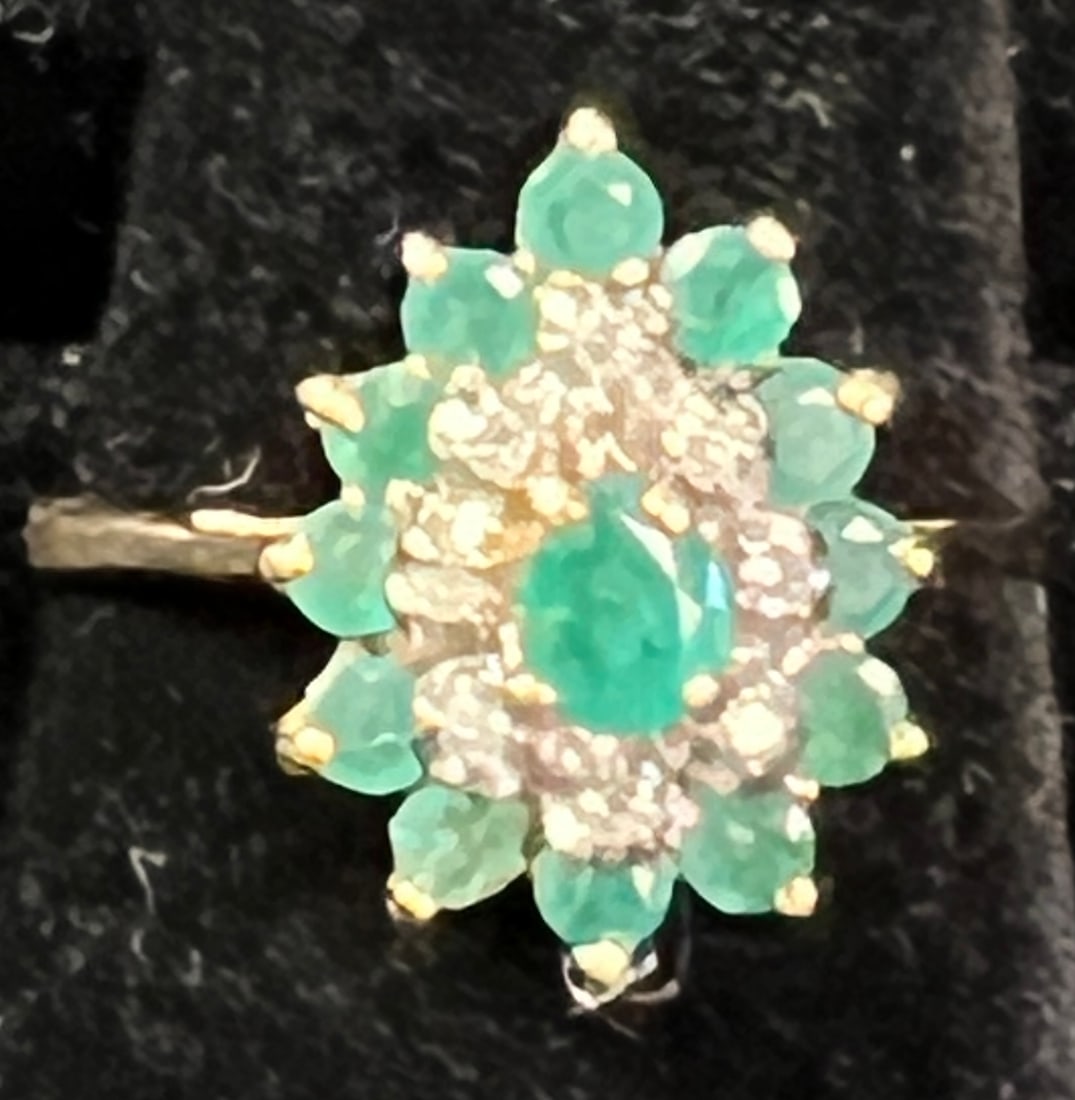 10K Gold Emerald & Diamond Women's Cocktail Ring: A 10k gold emerald and diamond women's cocktail ring. The ring features a central pear shaped emerald, surrounded by a row of diamonds and an outer row of emeralds. The ring is a size 8 and weighs
