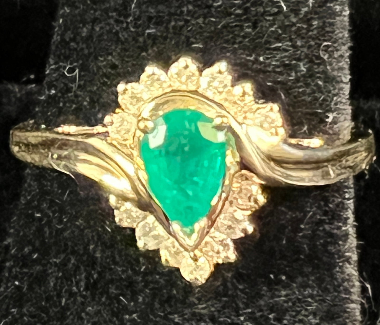 14K Gold Emerald and Diamond Ring: A 14k gold emerald and diamond ring features a pear-shaped emerald at the center flanked by small single-cut diamonds. Ring is in excellent condition, size 7.75 and weighs 2.9grams.
