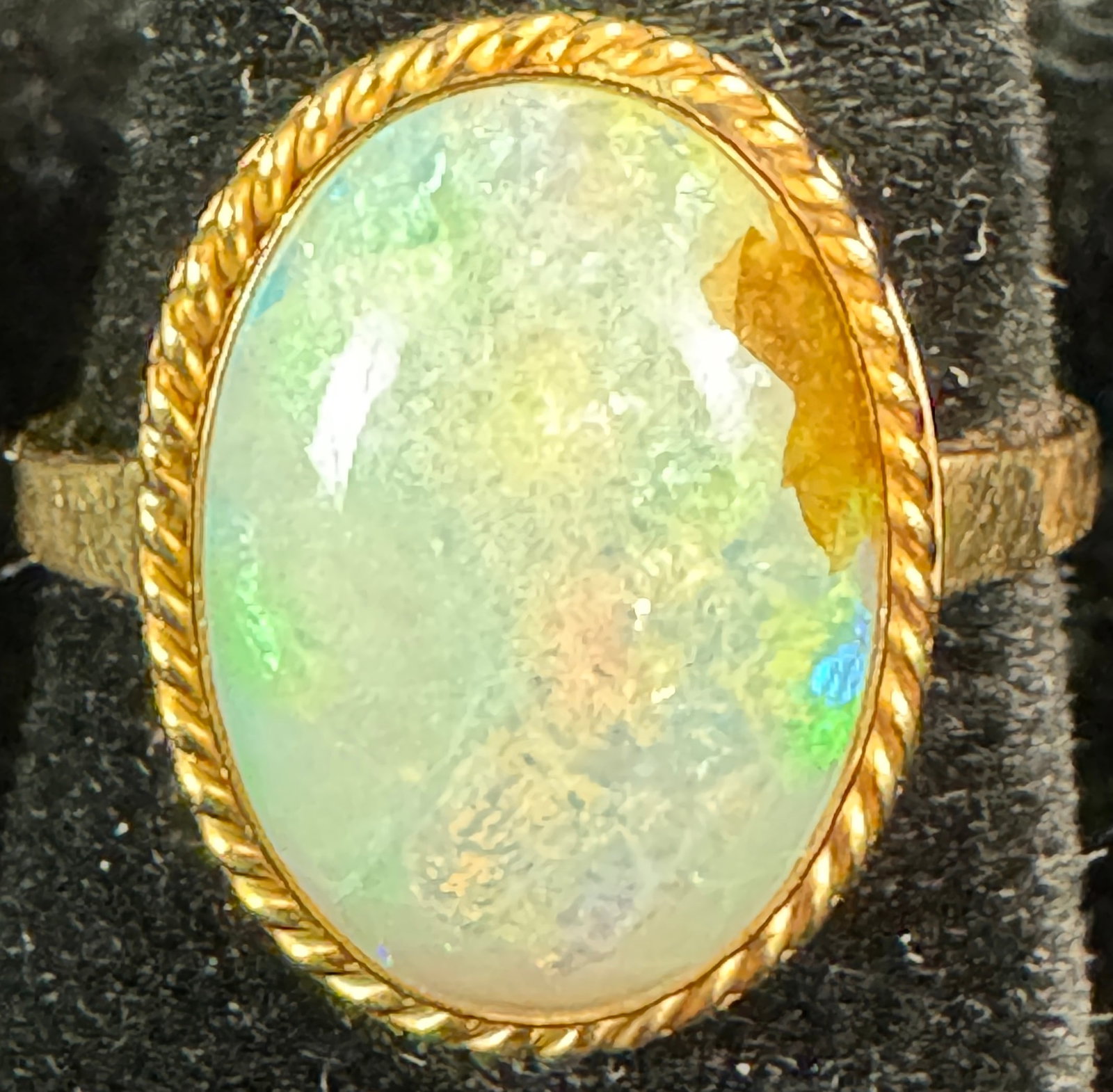 14K Opal Cabochon Women's Ring: A 14k gold ladies ring featuring a stunning opal cabochon surrounded by a gold rope chain border. This ring is a size 5 and weighs 2.61grams.
