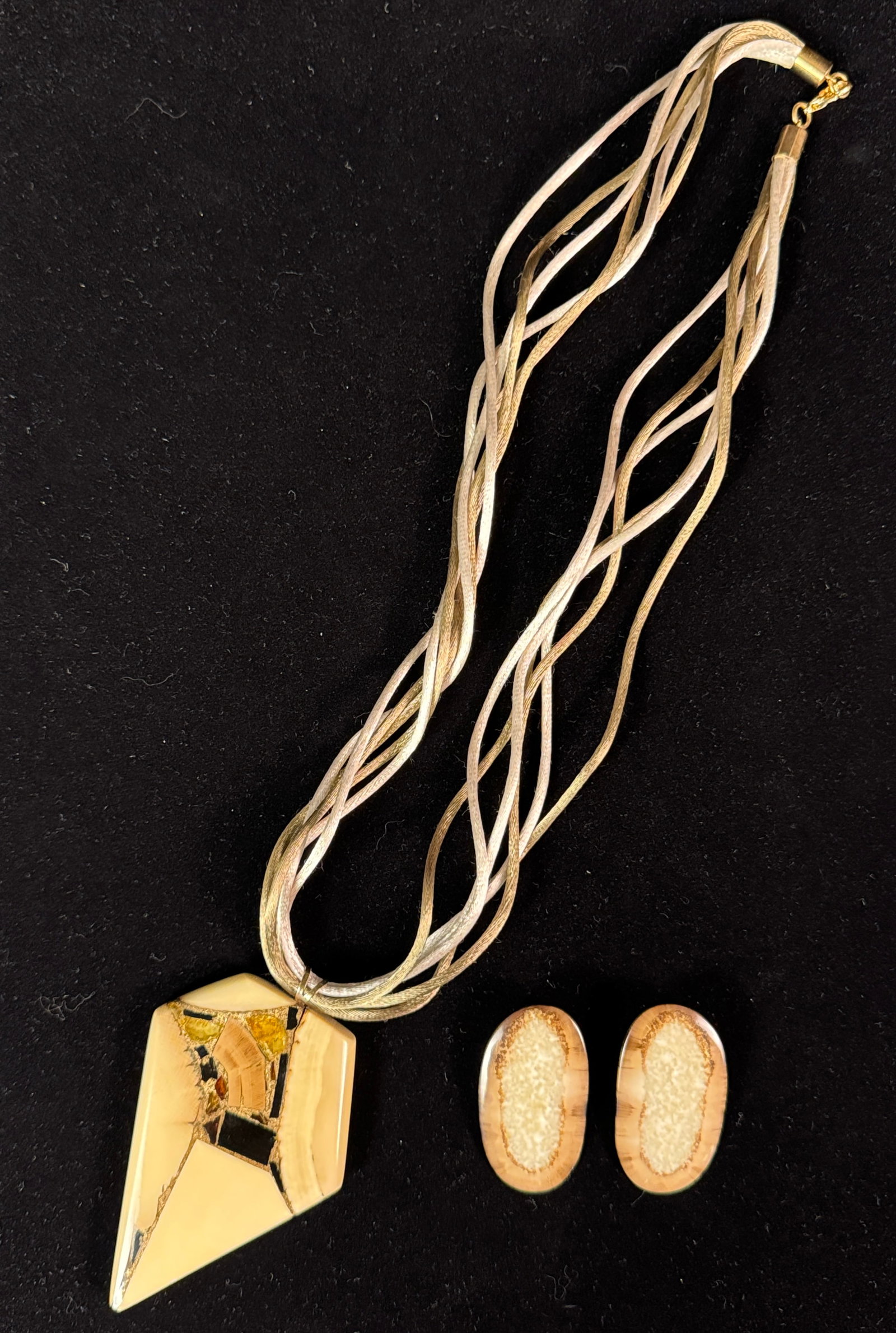 Alfred Cook 24K Gold and Mammoth Tusk Artisan Pendant: A pendant composed of mammoth tusk inlayed with 24K gold and precious stones. The bezel is 14K and the pendant is set with polished resin. The pendant was made by artist Alfred Cook based out of Vanco