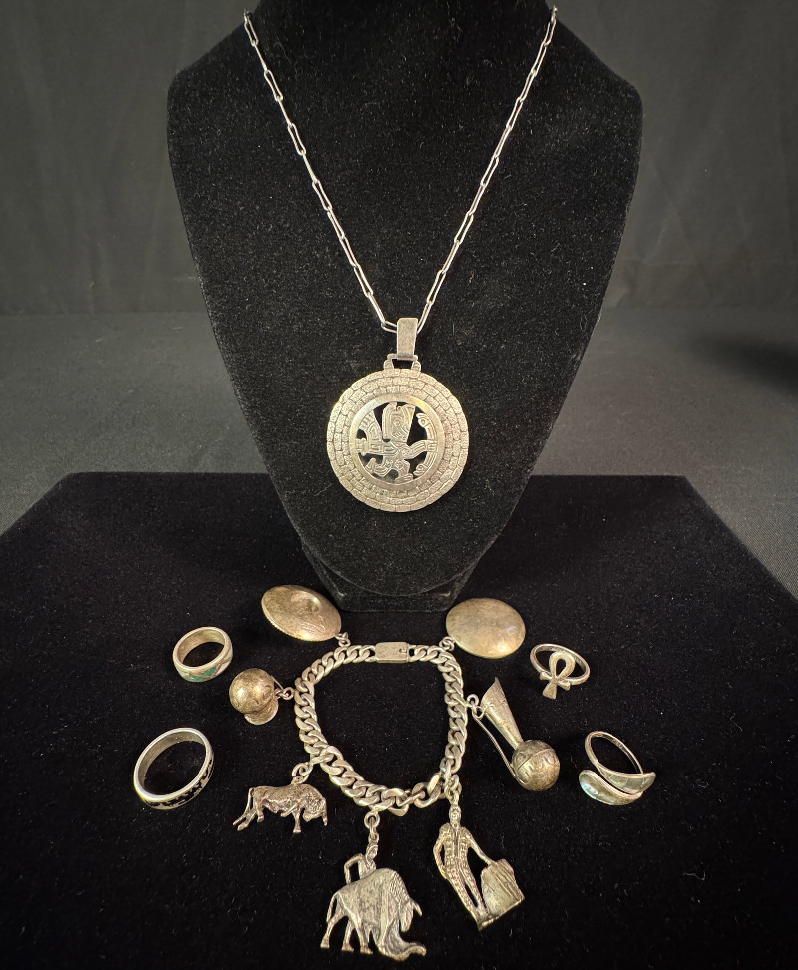 Mexican Sterling Charm Bracelet, Necklace & Rings: A group to include an outstanding vintage Mexican sterling charm bracelet with a variety of hand crafted charms. Also included is a Southwest stylized sterling medallion necklace, and four silver ring
