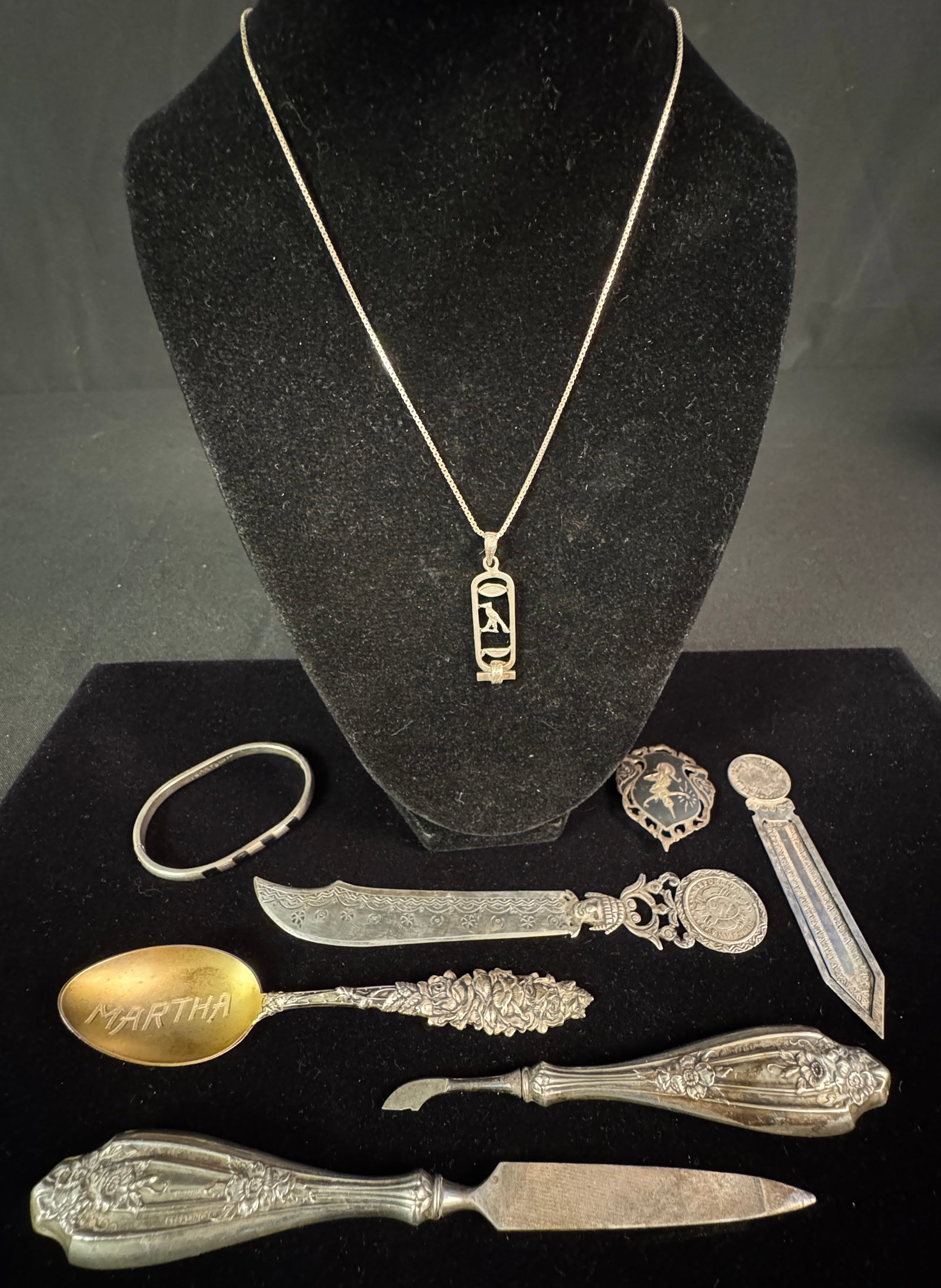 Group of Assorted Sterling Utensils, Jewelry & More: A group to include two sterling filled handled pieces of a Victorian vanity set, sterling souvenir spoon with the name Martha, Bolivia coin bookmark, Bolivia coin letter opener, Siamese sterling brooc