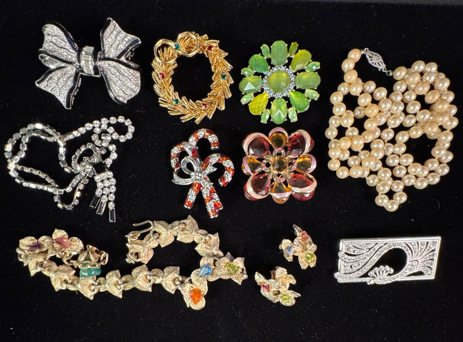 Group of Costume Jewelry to Include Eisenberg, Swoboda, and More: A group of costume jewelry to include an Eisenberg rhinestone necklace, a Swoboda multi-color stone necklace with matching earrings, a string of Art Deco faux pearls, and six costume jewelry brooches,