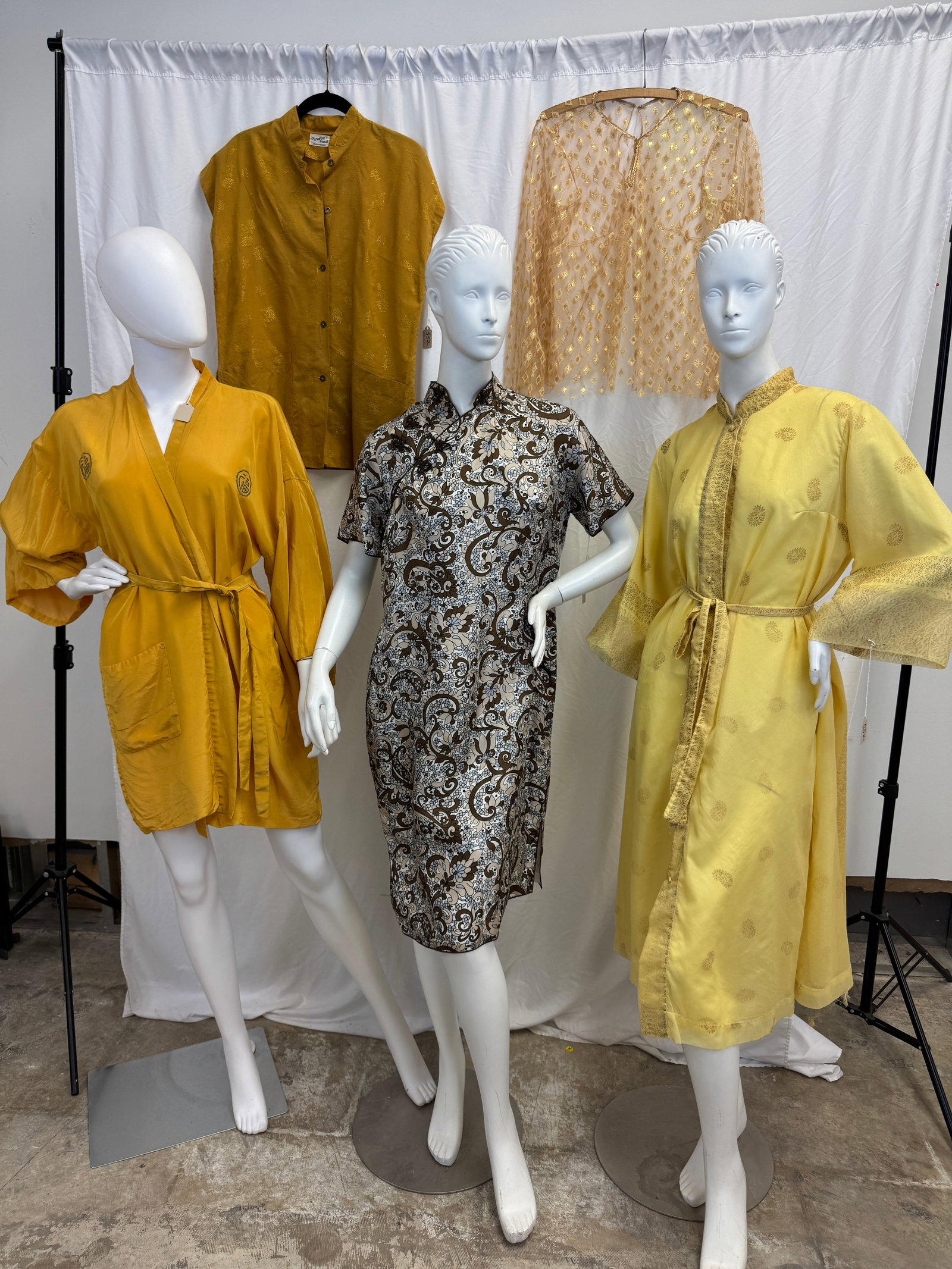Asian Style Vintage Garments c1960's: A group of vintage Asian style garments to include a short embroidered saffron yellow robe, a yellow Dorian paisley print robe, a silk paisley and floral cheongsam sleeveless dress, a sleeveless golde