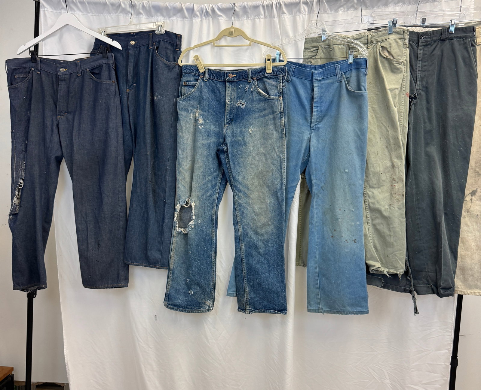 Group of 7 Pairs of Vintage Denim and Work Pants c1960/80's: A group of men's vintage jeans and work pants to include Dakota 80's blue jeans, khakis, and more. All in as found condition to include holes, wear, some with paint splashes