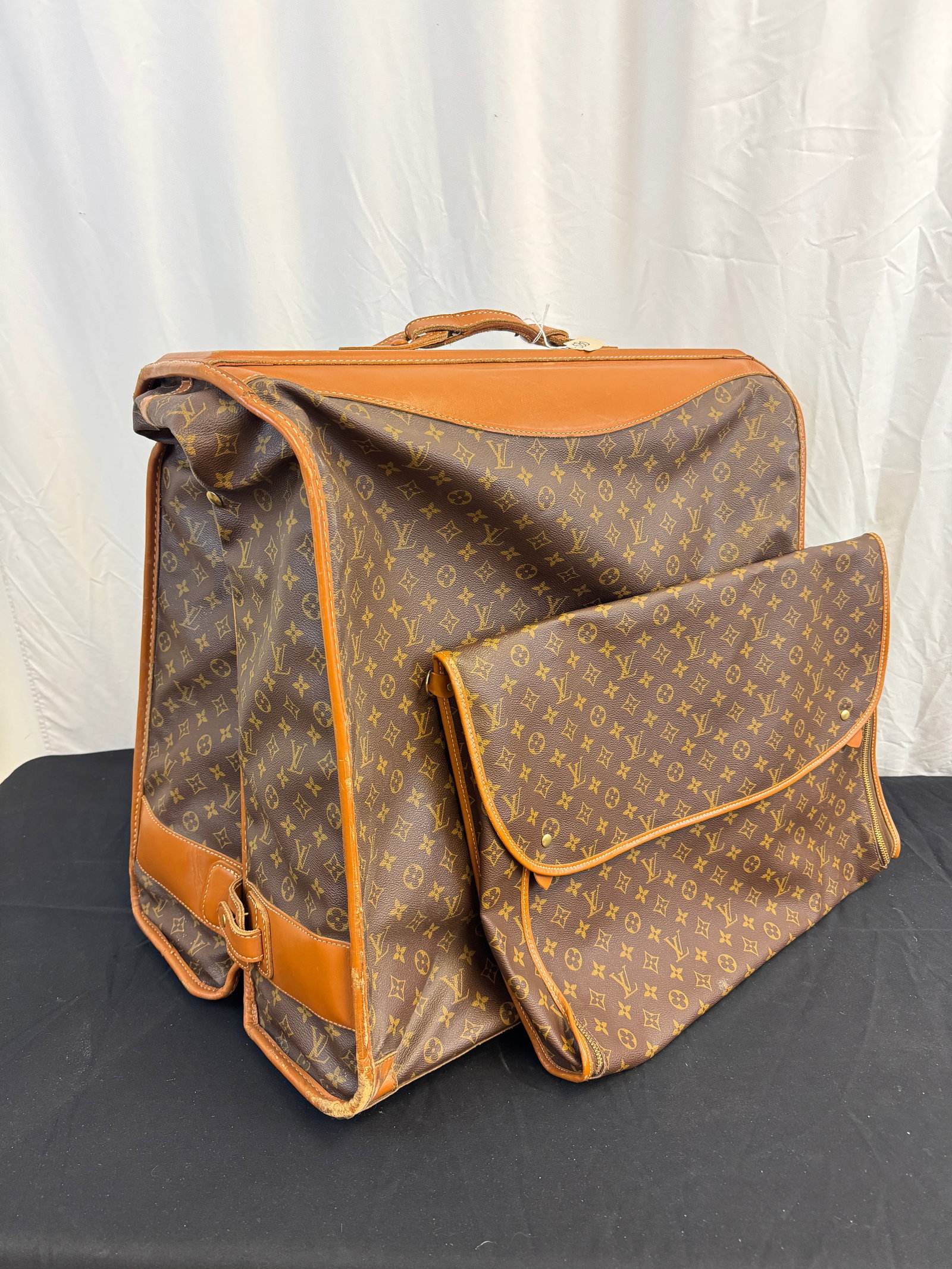 Louis Vuitton Bi Fold Garment Bag c.1970's: A Vintage Louis Vuitton bi-fold monogram garment bag c.1070's that features original hangers and 2 extra interior bags in very good condition. It measures 23" tall X 23" across X14" deep.