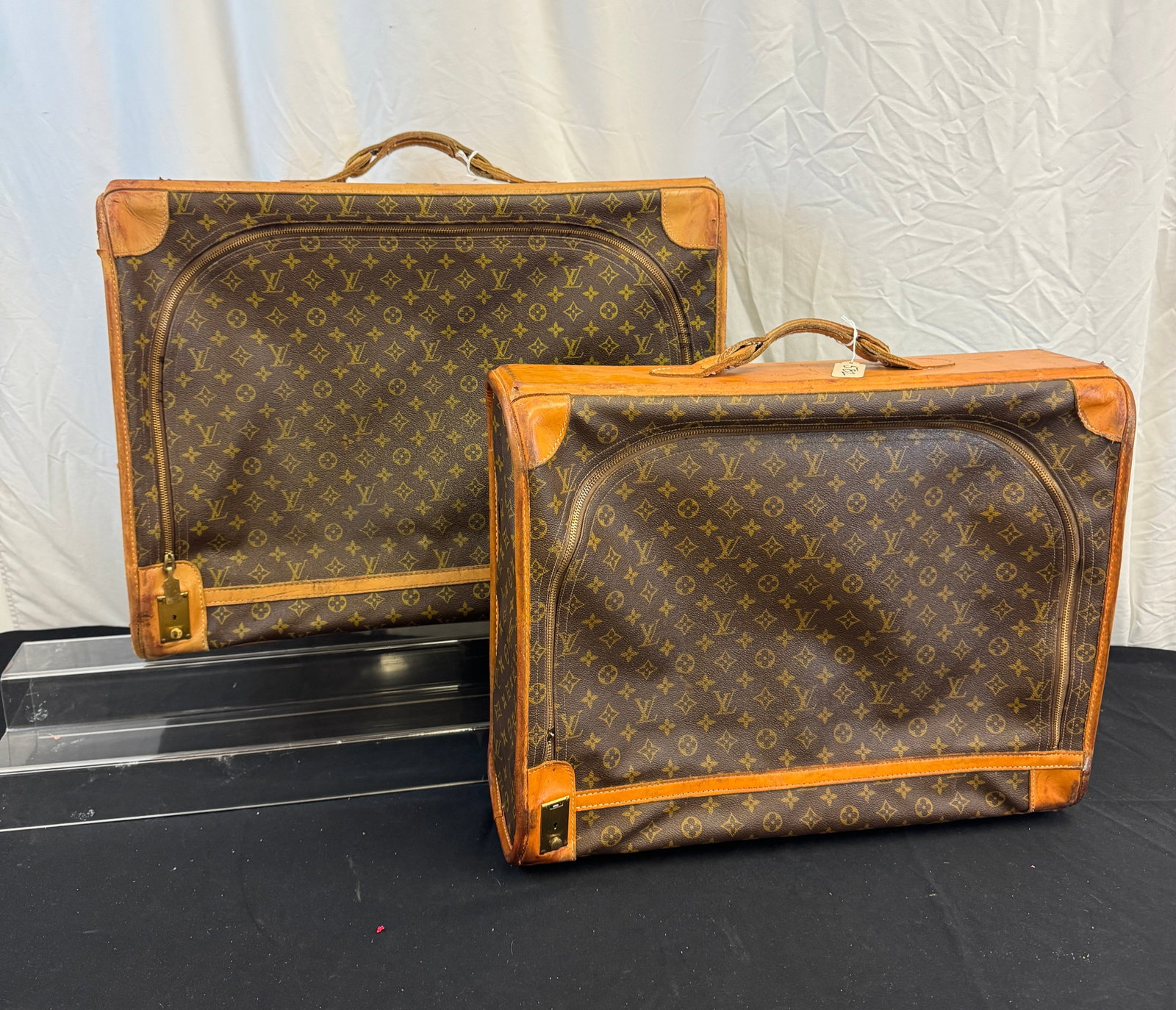 2 Louis Vuitton Vintage Suitcases c.1980's: Two Louis Vuitton vintage suitcases to include a monogram canvas body Pullman 65 suitcase with leather accents in used condition ( missing pull for zipper, but zipper is working) that measures 19" tal
