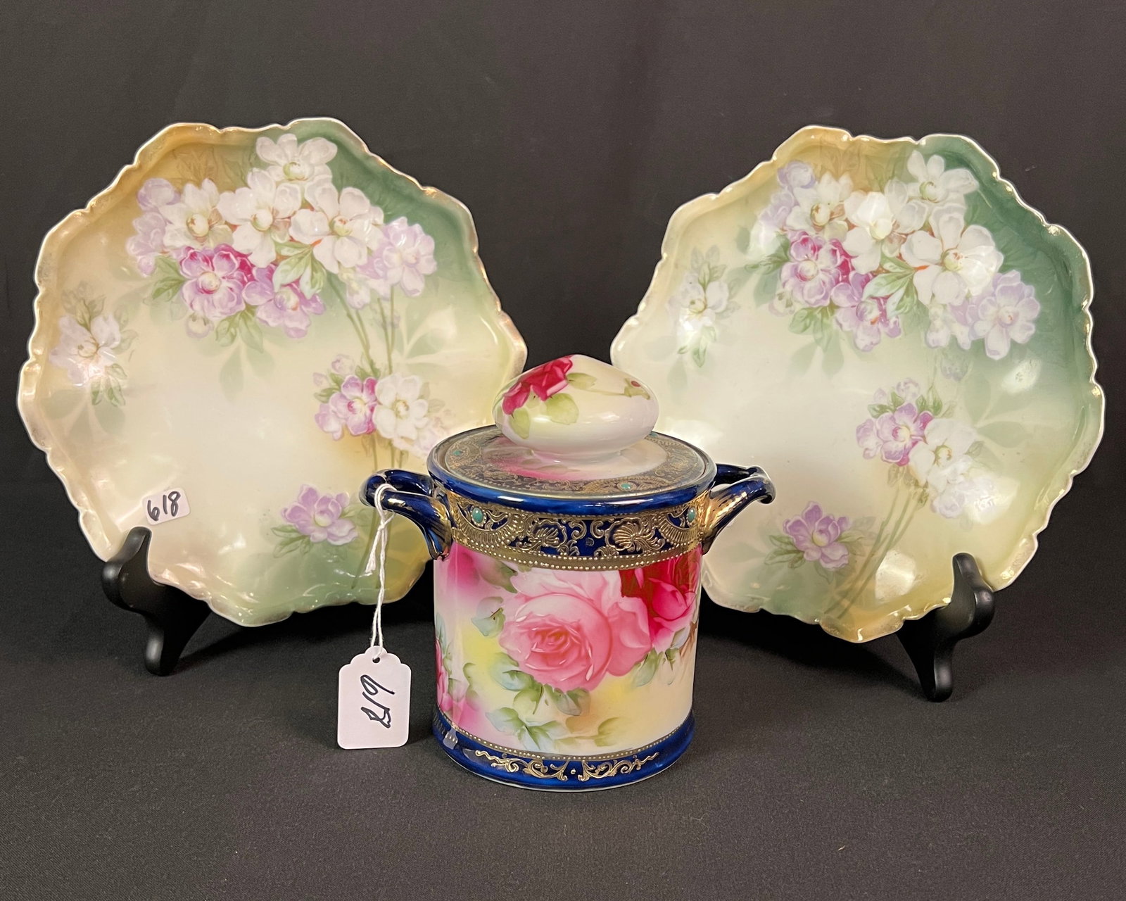 RS Prussia & Nippon Items: 2 hand painted floral RS Prussia plates w/ scalloped plates (9" round) along with a deep cobalt and rose painted Nippon humidor with gold beading (6.5" round).