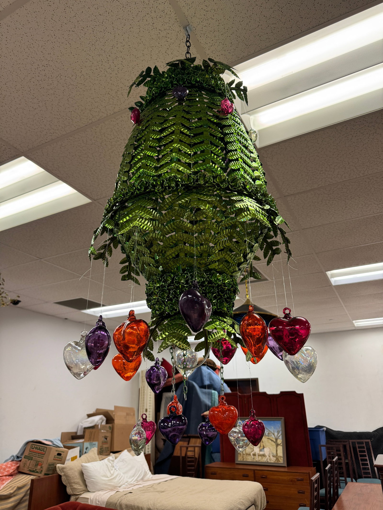 Vintage Mexican Pressed Tin Chandelier w/ Hand Blown Glass Heart Prisms: A Folk Art Mexican pressed tin analyzed metal chandelier that features green hand worked fronds, flowers and hand blown multi colored glass prisms in excellent condition.