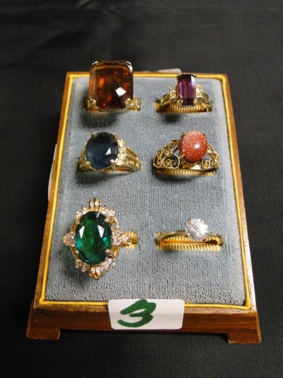 6 rings with colored stones in a 1920's ring holder.: 6 rings with colored stones in a 1920's ring holder.