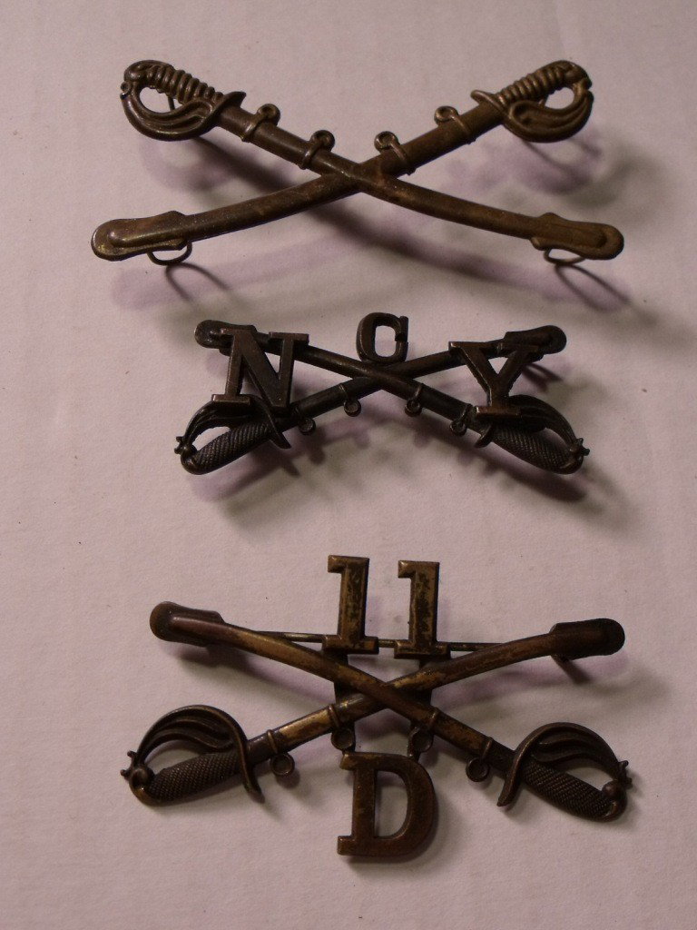 3 Cavalry Badges: Each cavalry badge shows crossed swords. One is from New York, one has a number 11 and a D, the third one is just crossed swords.