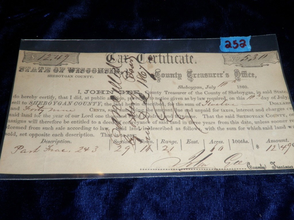 1860 Tax Certificate: Tax certificate for $12.49 from the State of Wisconsin. Signed by John Gee County Treasurer. Handwritten across the front "Cancelled by order of board in Dec. 1867.